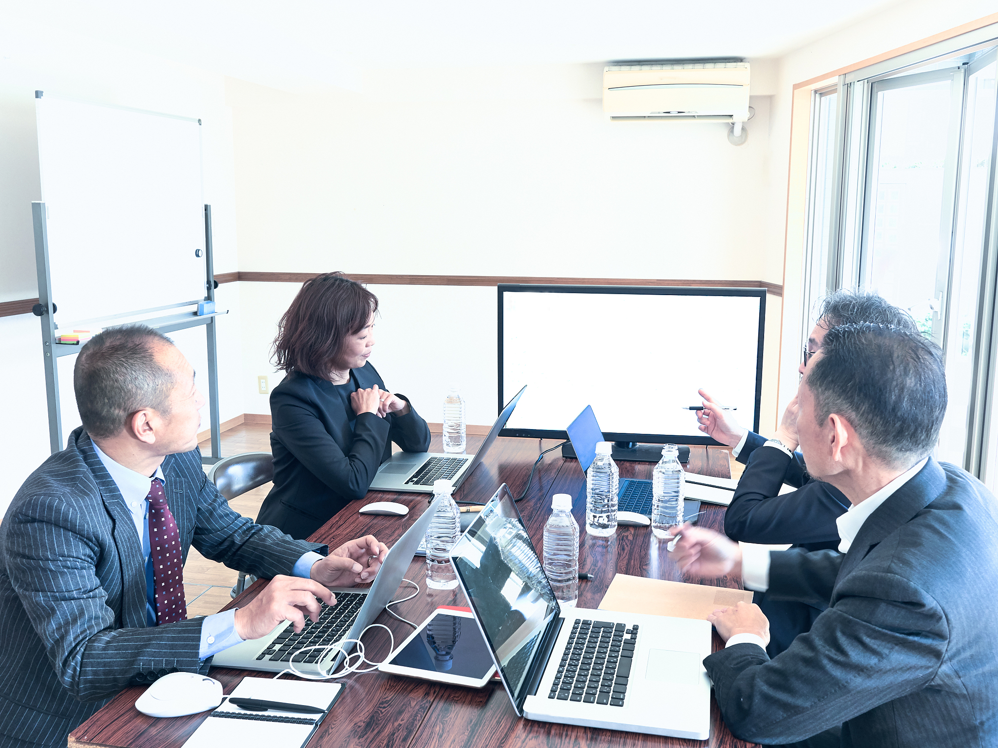 men and women are talking at the meeting while using the monitor