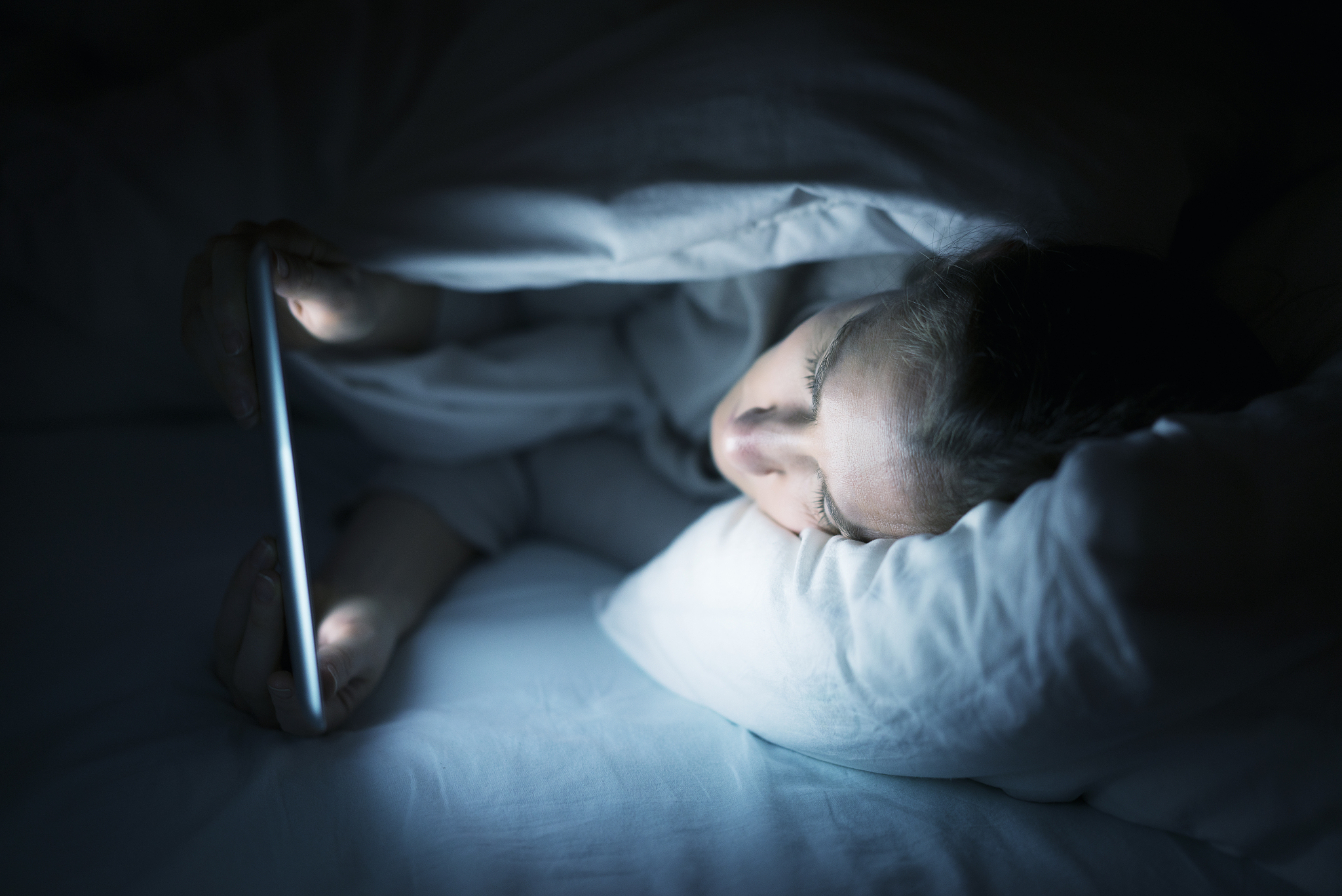 woman using tablet pc in bed at night