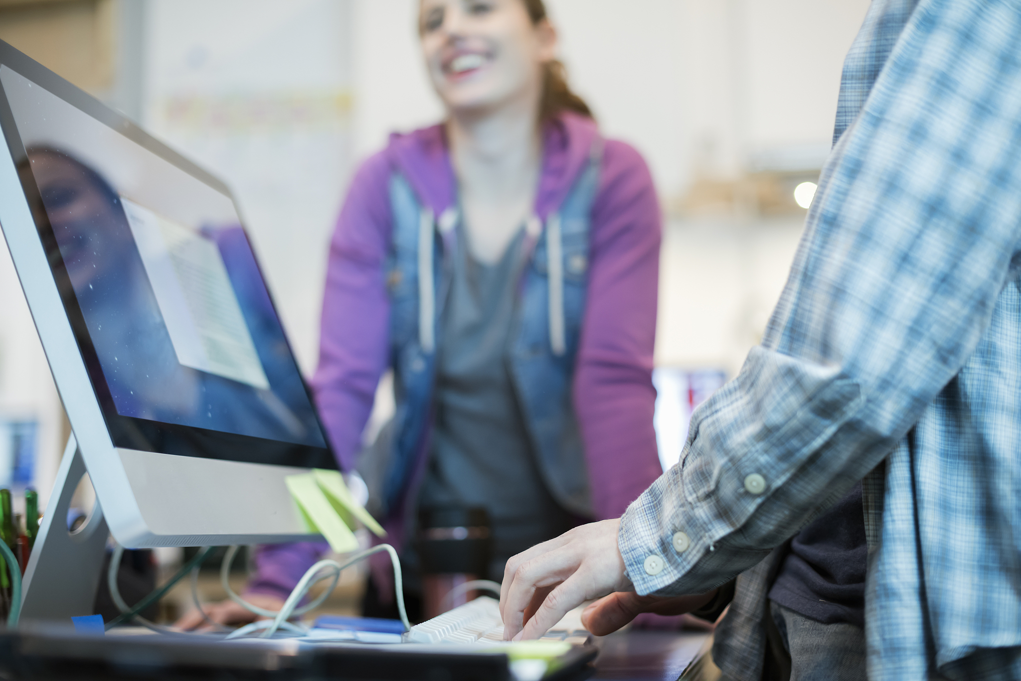 two people at a computer repair shop, one typing and checking a 