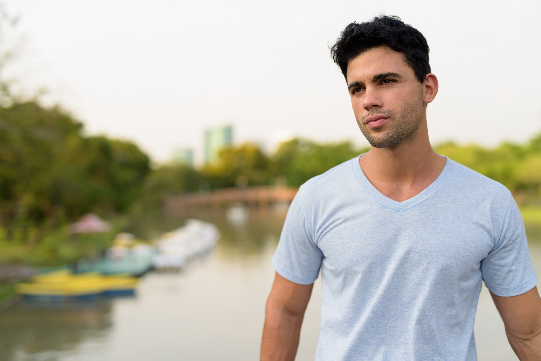 portrait of young handsome hispanic man relaxing at the park in 