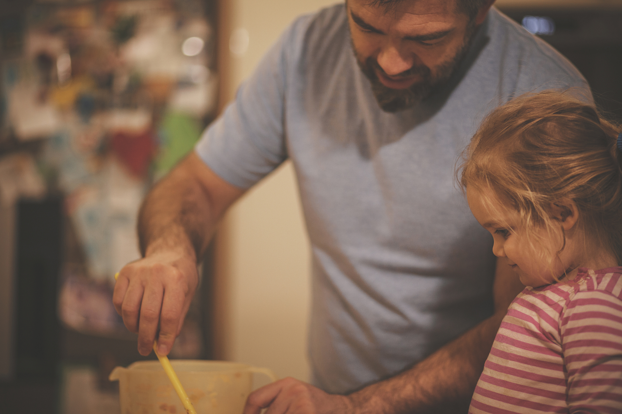 happy mid adult man and his toddler daughter preparing dinner to