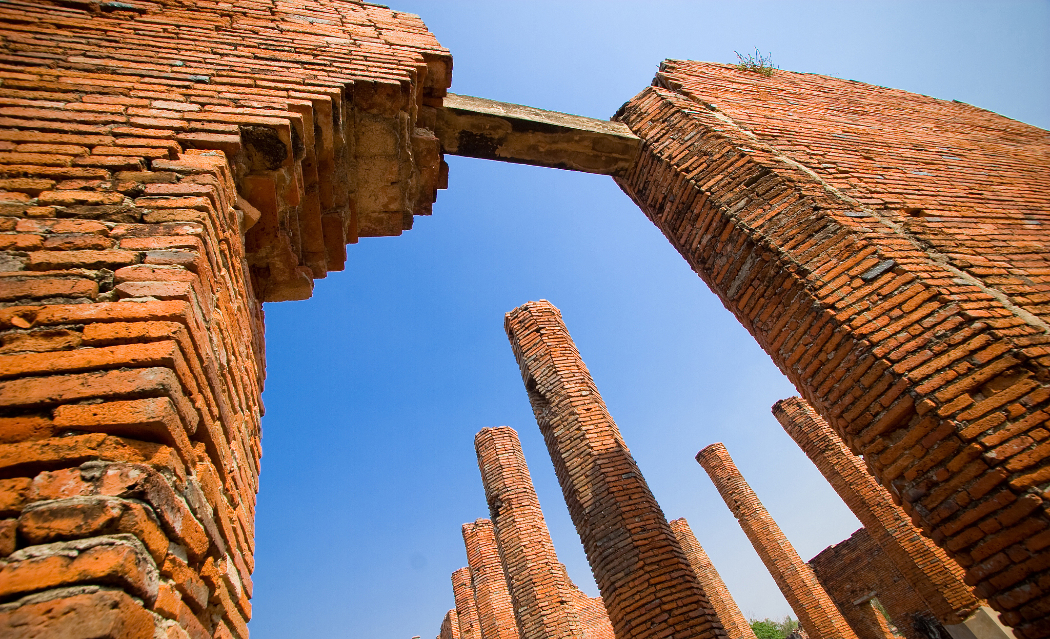 ruin orange brick wall and poles in ayutthaya historical park