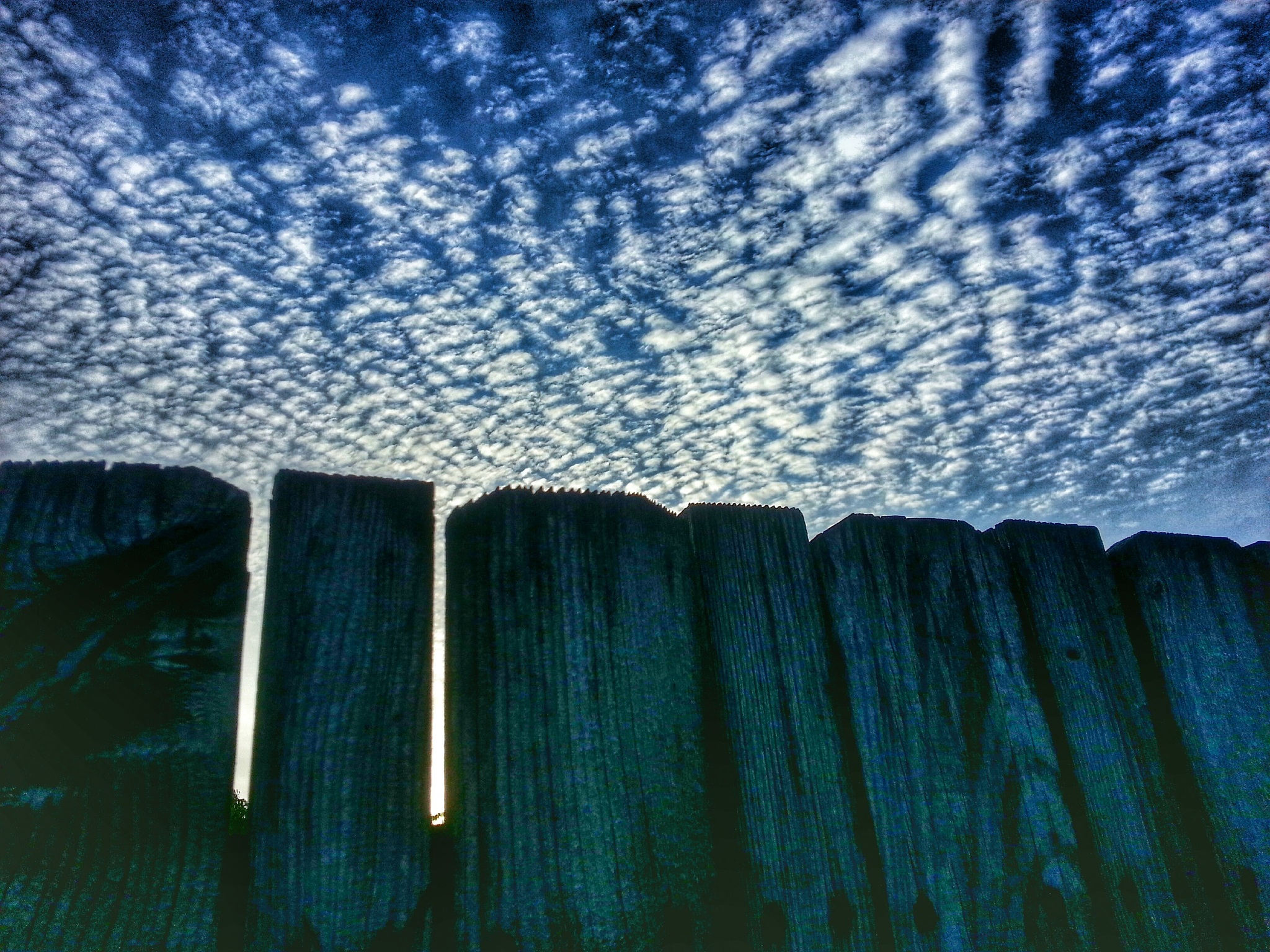 low angle view of fence against cloudy sky