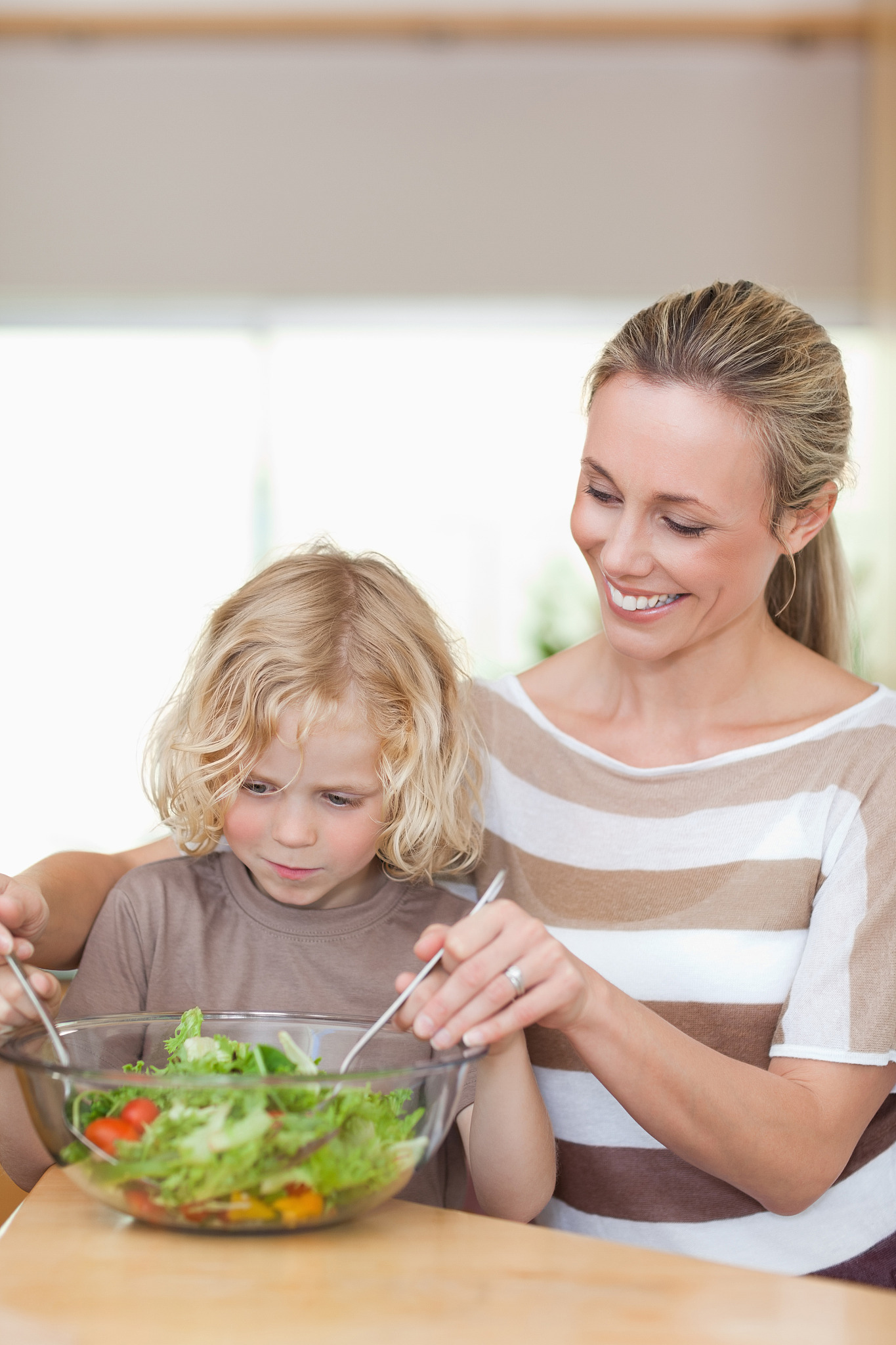 mother and son stirring salad together