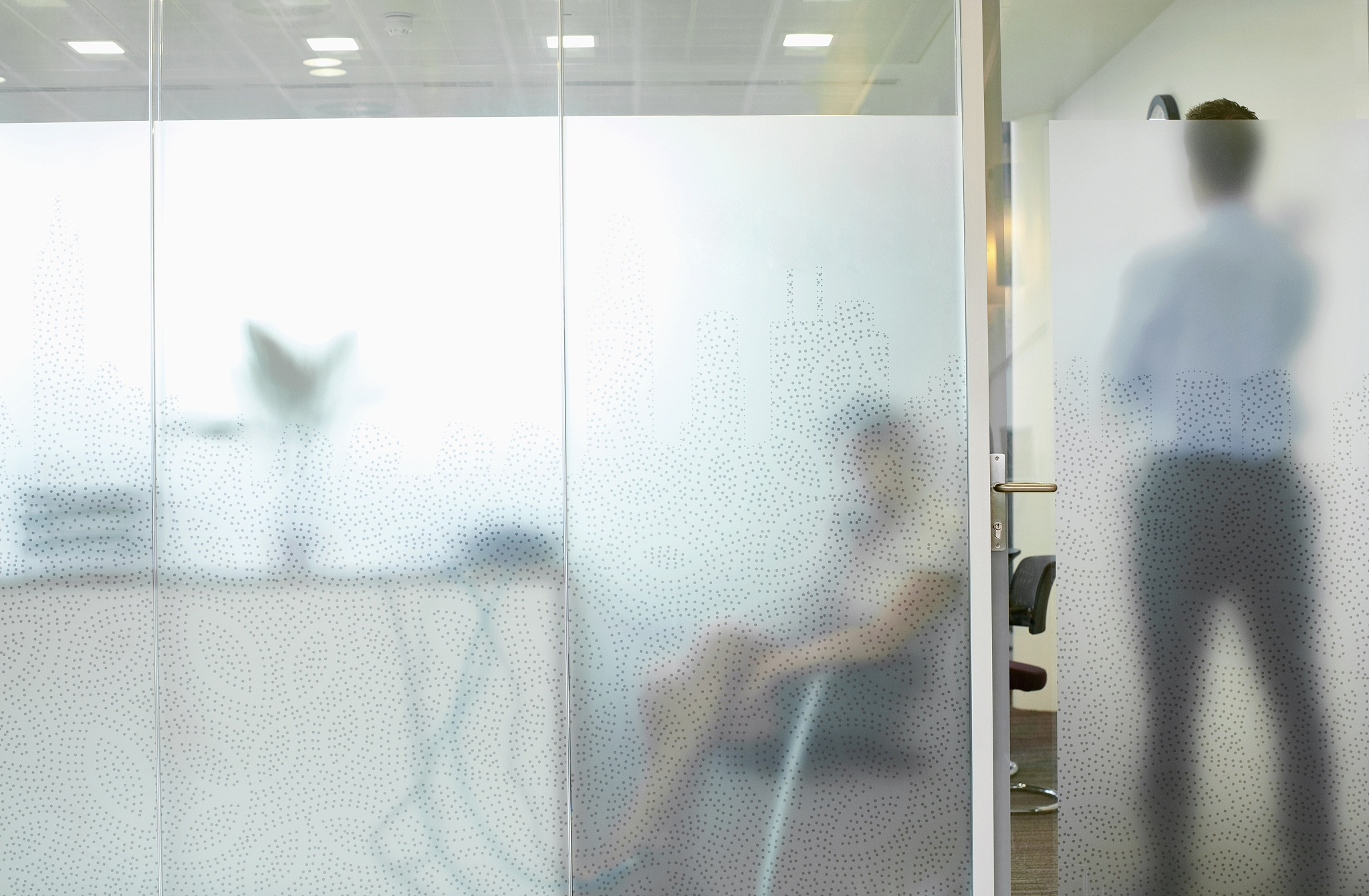 business executive standing behind glass door