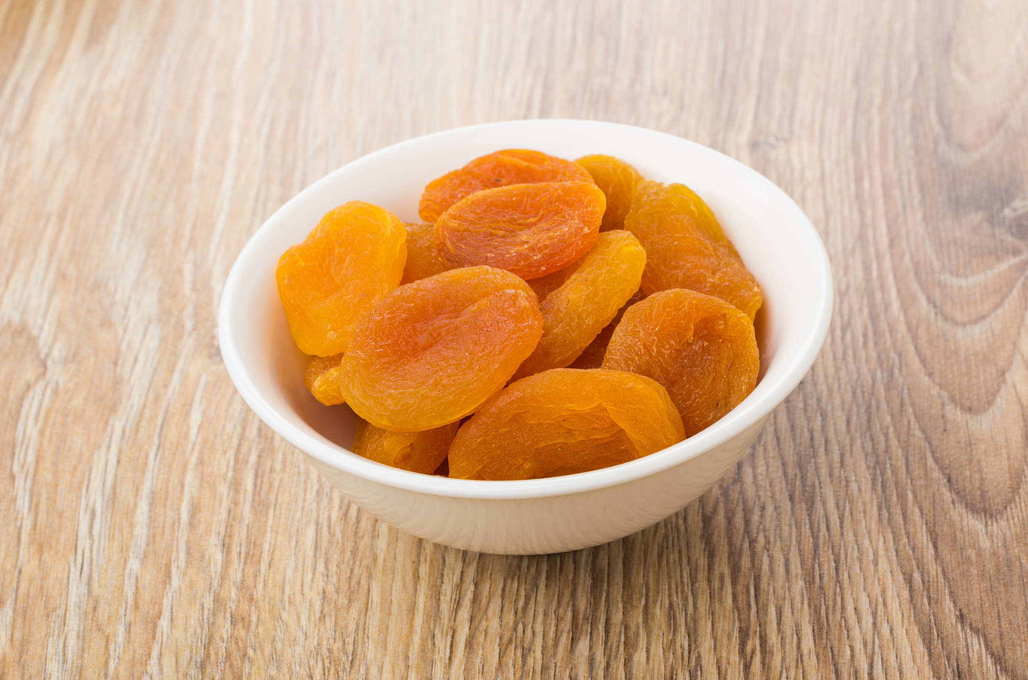 white glass bowl with dried apricots on table