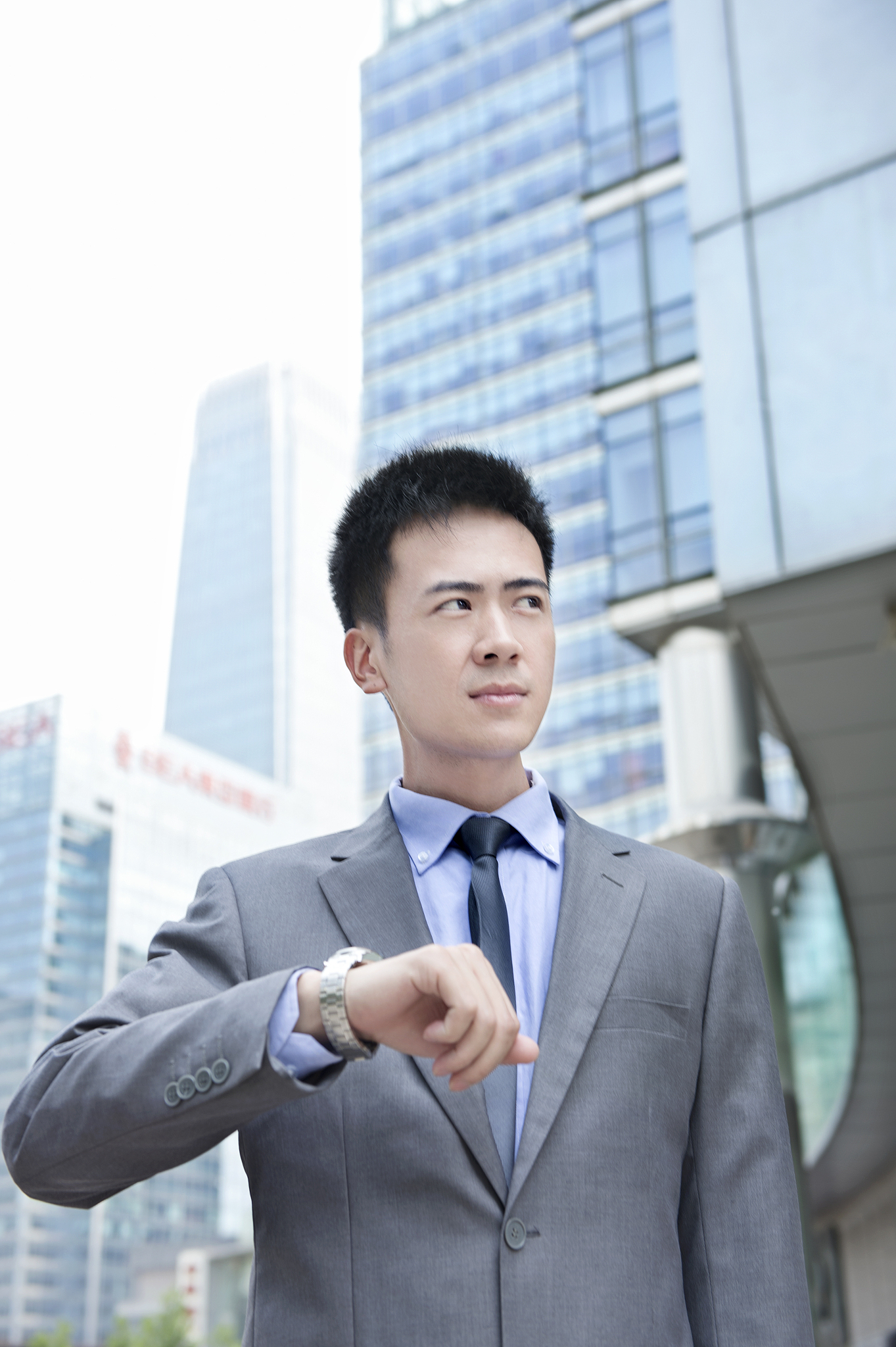 站在大楼前看时间的商务男士