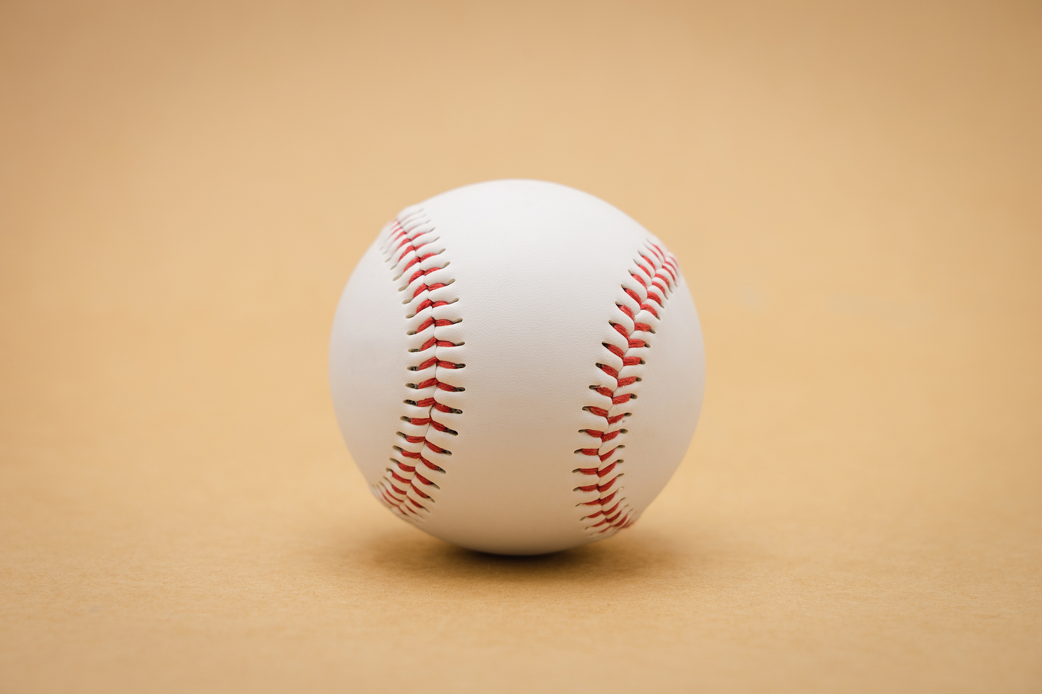isolated baseball on a brown background and red stitching baseba