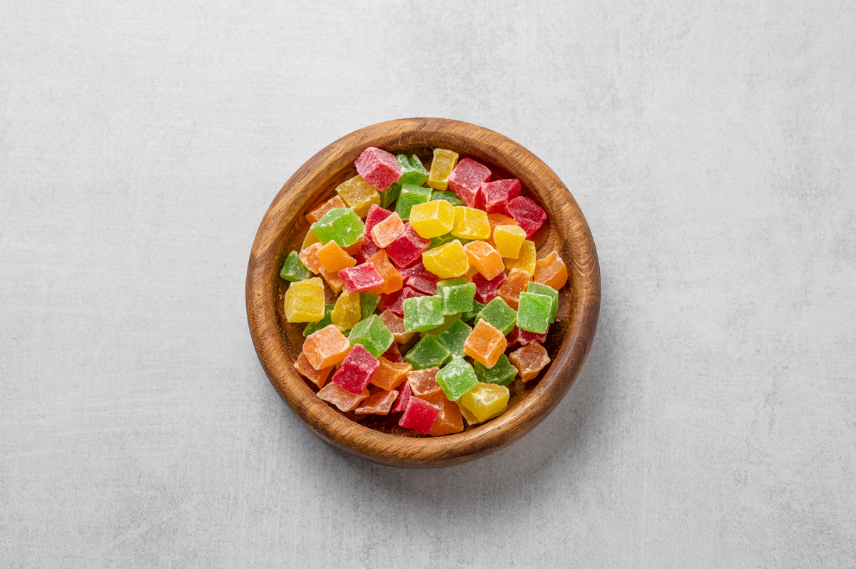 浅色纹理背景上木碗里的蜜饯混合水果.