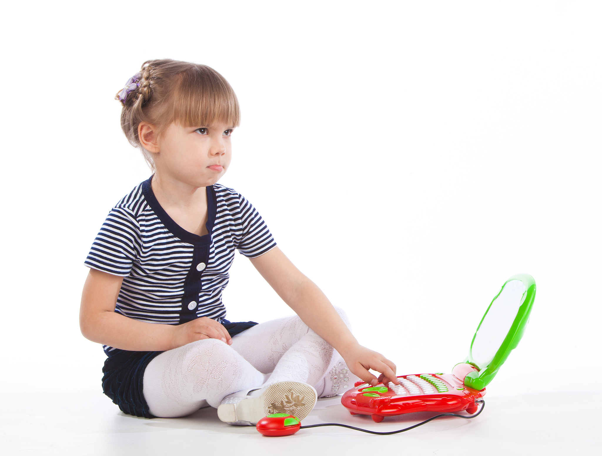 little girl is sitting on the floor with toy laptop