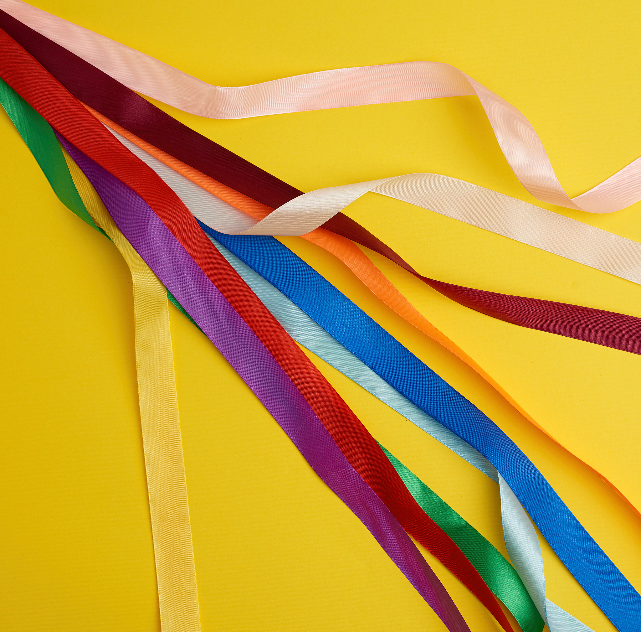 many silk multi-colored ribbons on a yellow background