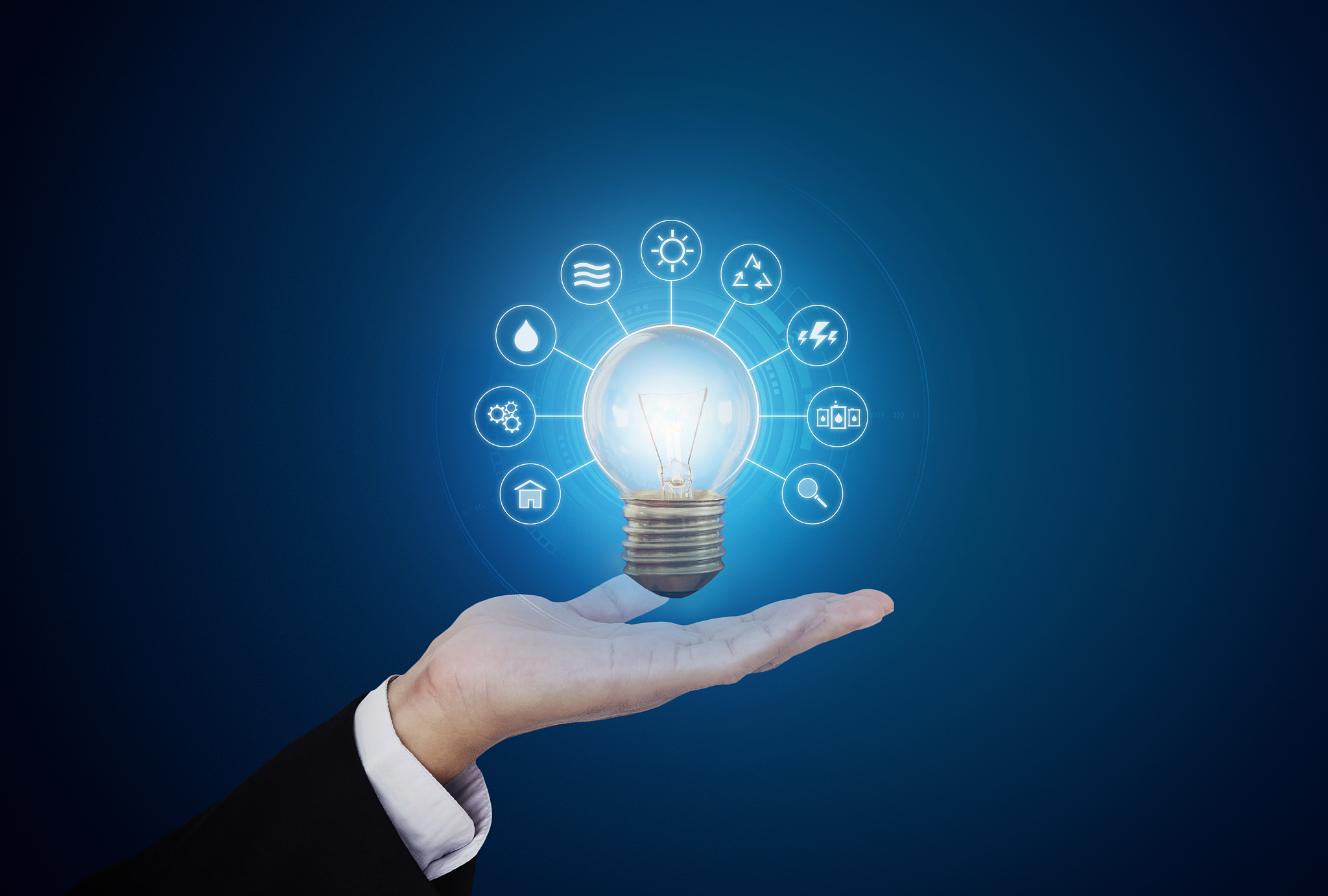 hand holding bright light bulb with energy resources icon, on bl