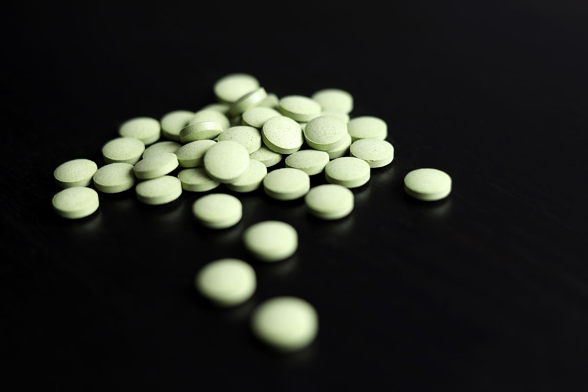 绿色药丸散落在深色的木桌上