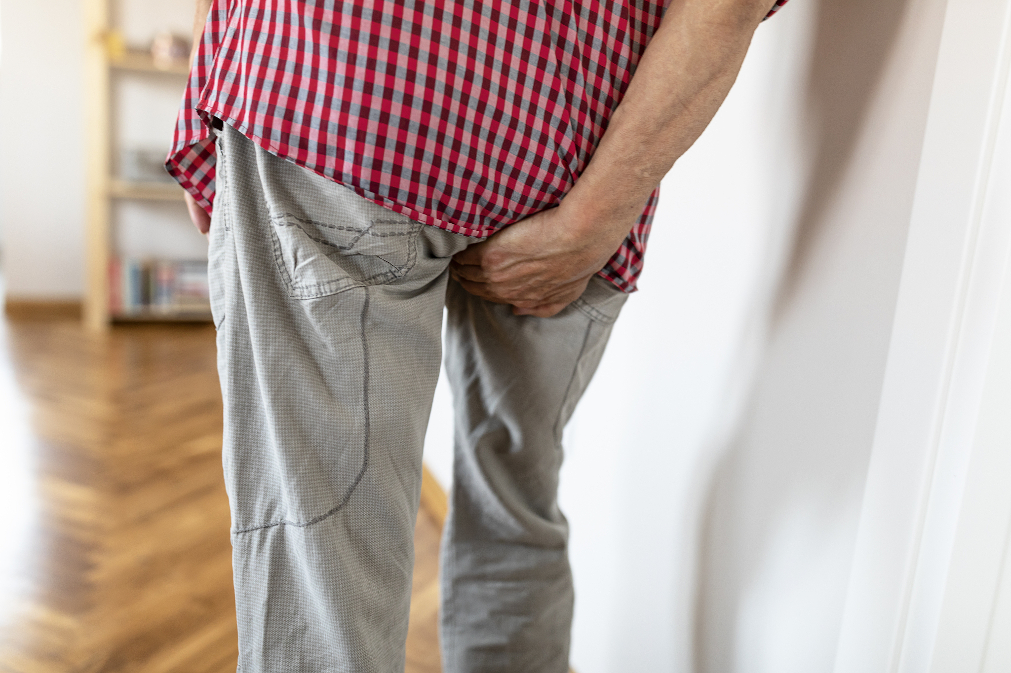 man with hemorrhoids holding his ass in pain
