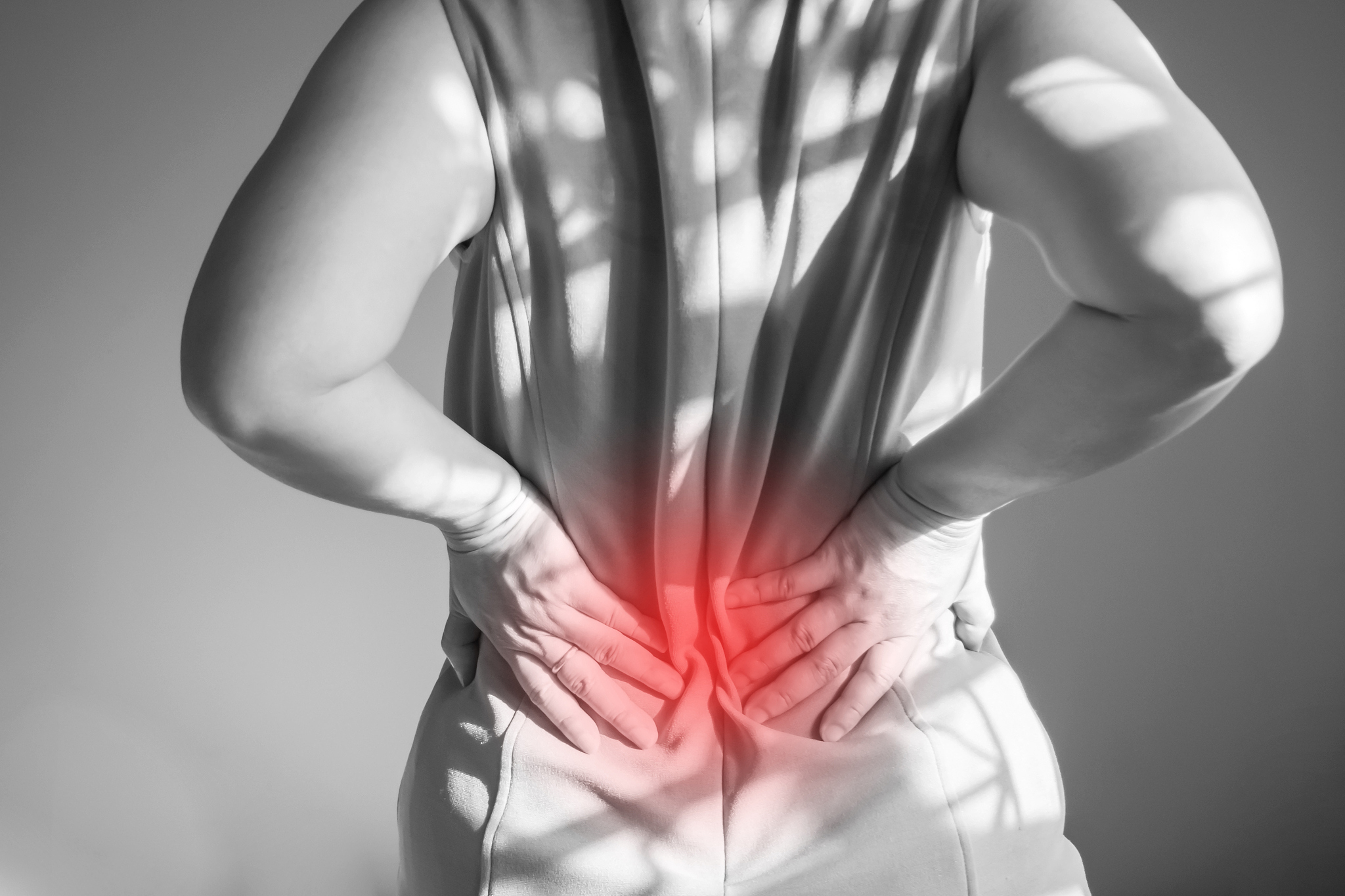 woman holding two hands on back. back pain at waist. symptoms of