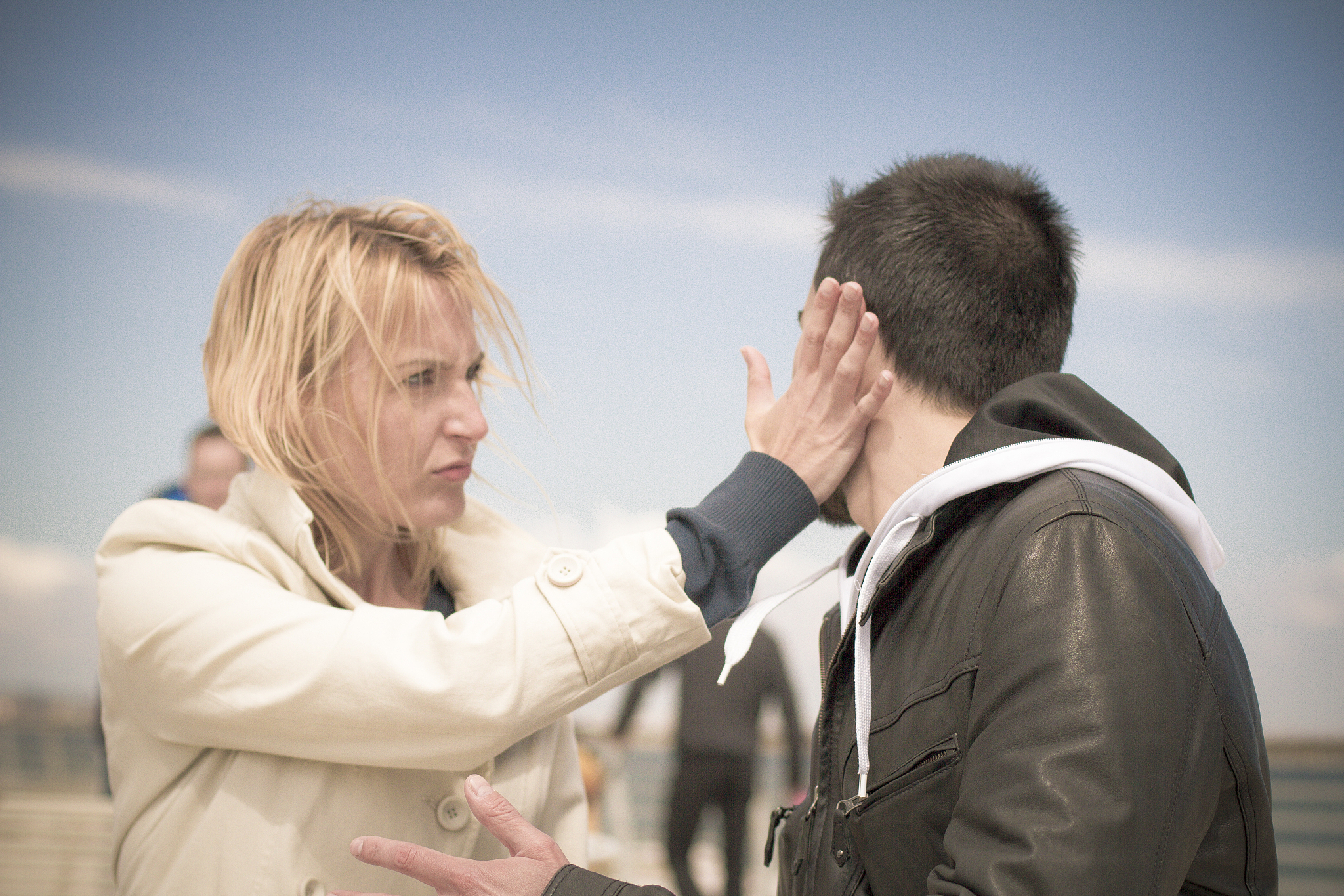 young woman slapping man at wharf