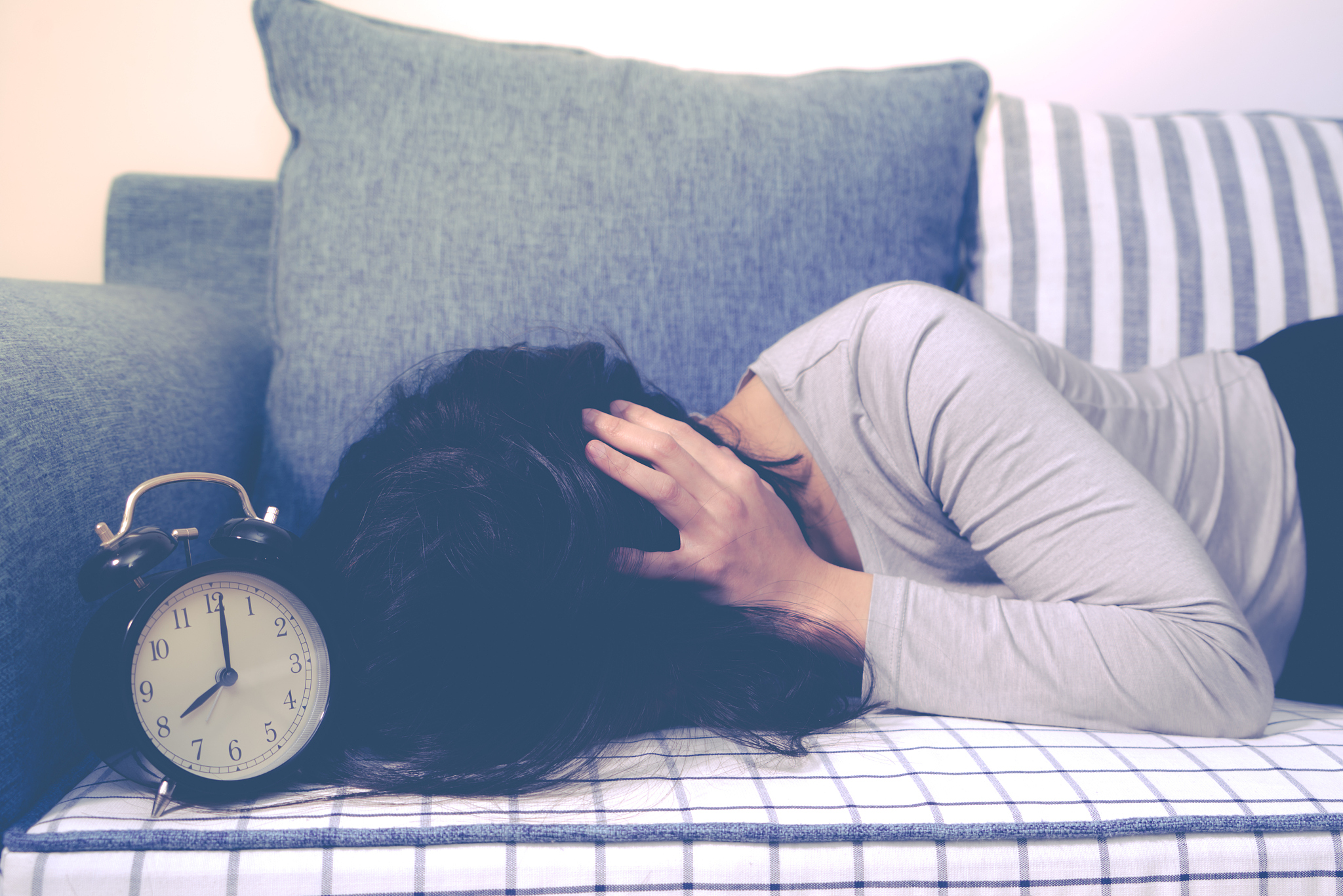 lazy women is laying down on the sofa after the clock alarm, lat