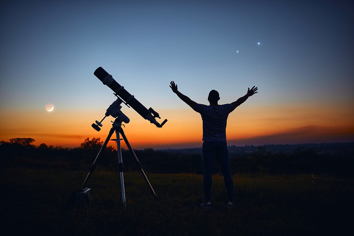 一个人的剪影,望远镜和星空下的乡村.
