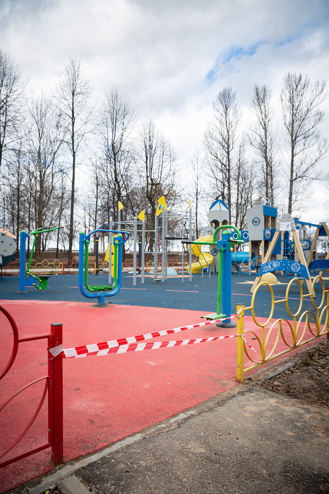 empty playground in a city park, fenced with warning tapes of re