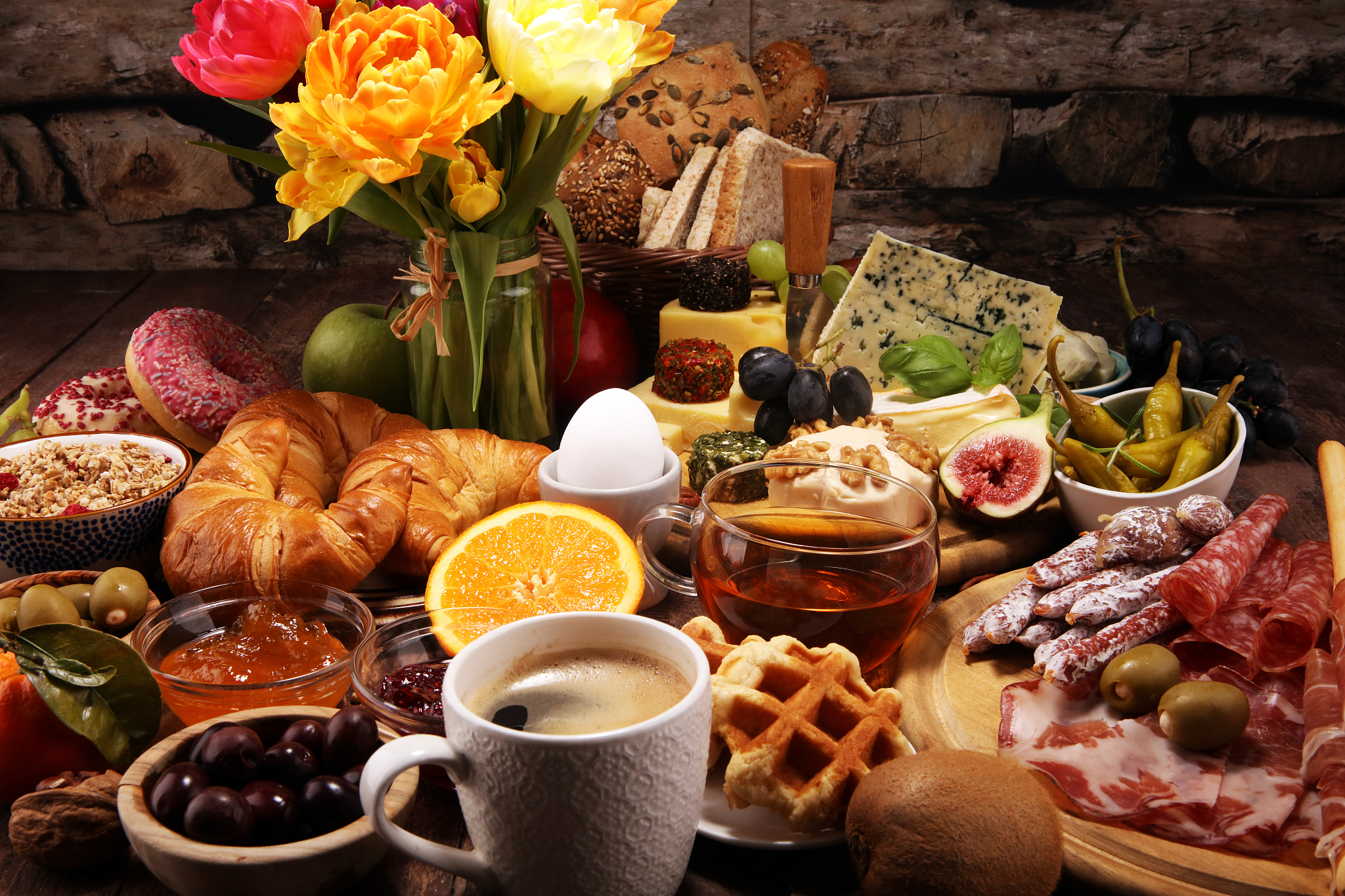 breakfast on table with bread buns, croissants, coffe and eggs
