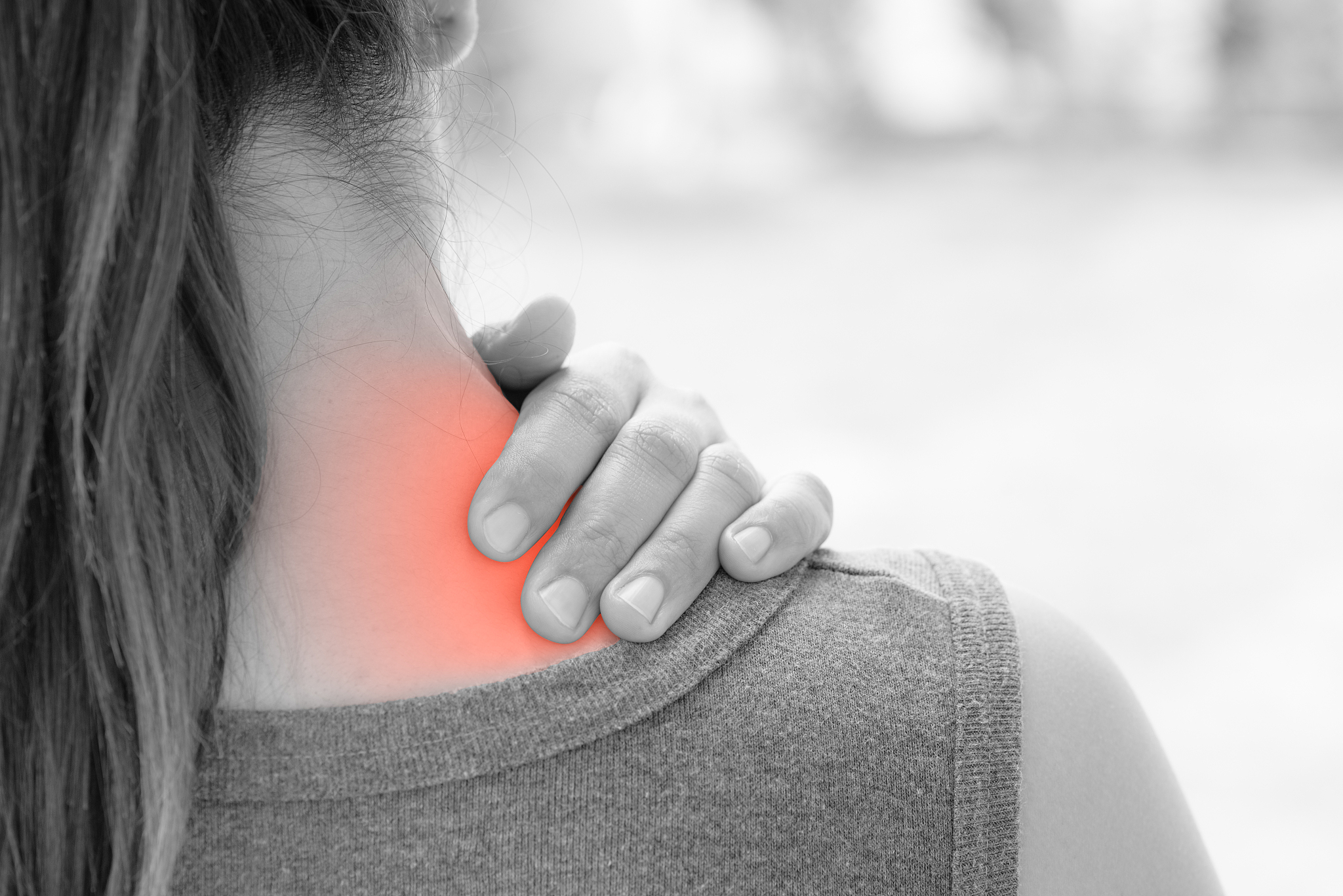 closeup woman neck and shoulder pain and injury with red highlig