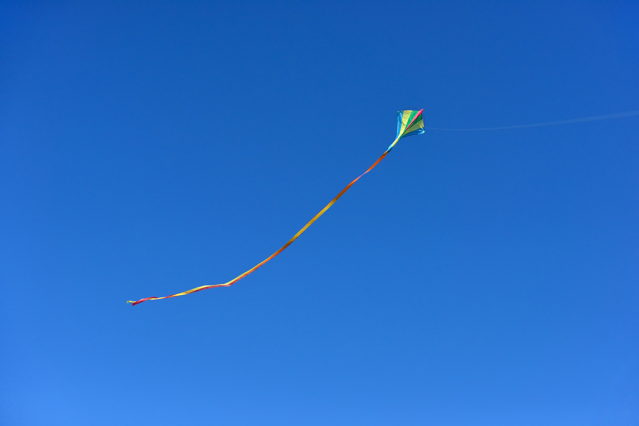 a kite flies in a clear and blue sky