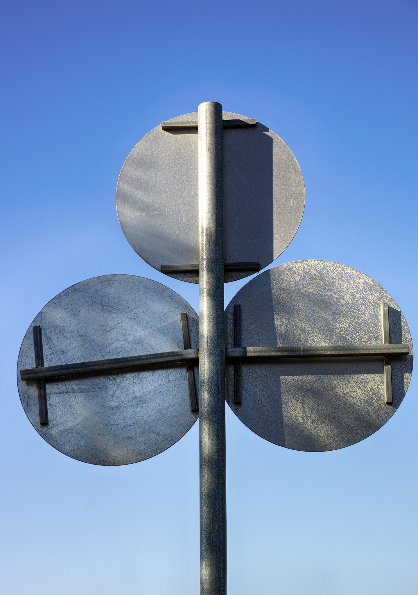 back view of three road signs against blue sky.