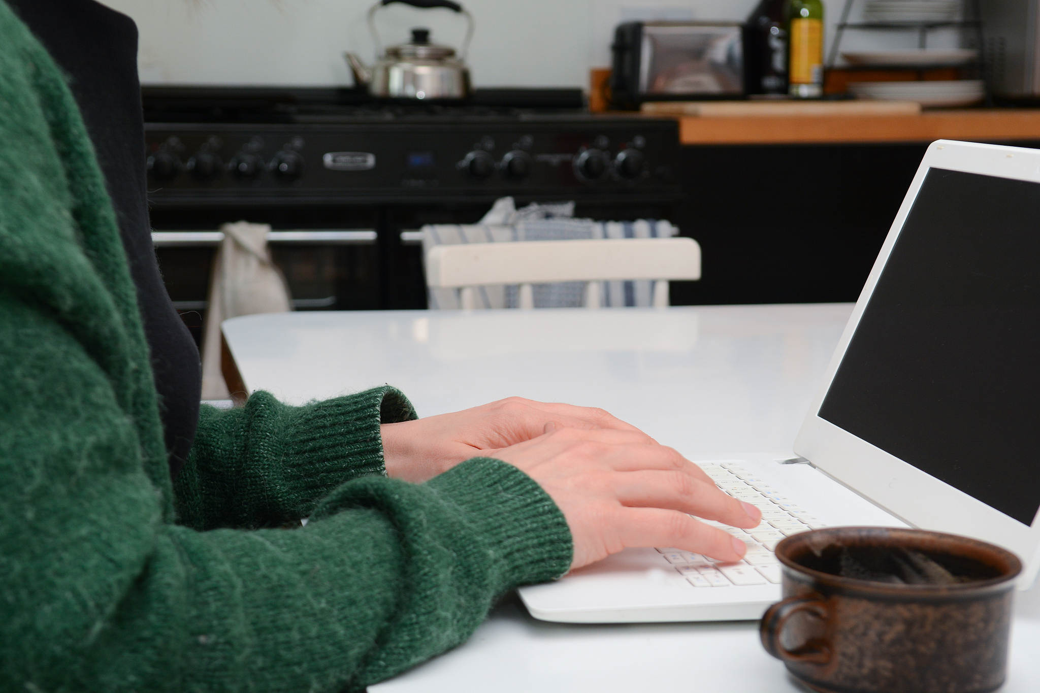 woman at home in kitchen using laptop computer