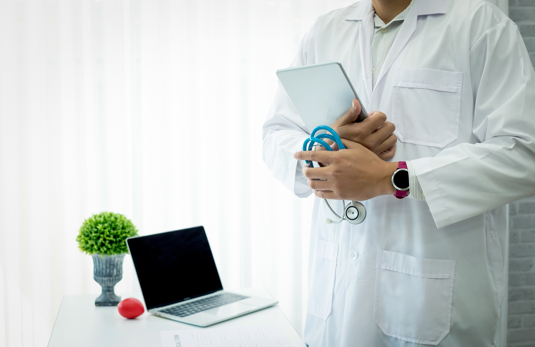 doctor stand holding the tablet in the office.