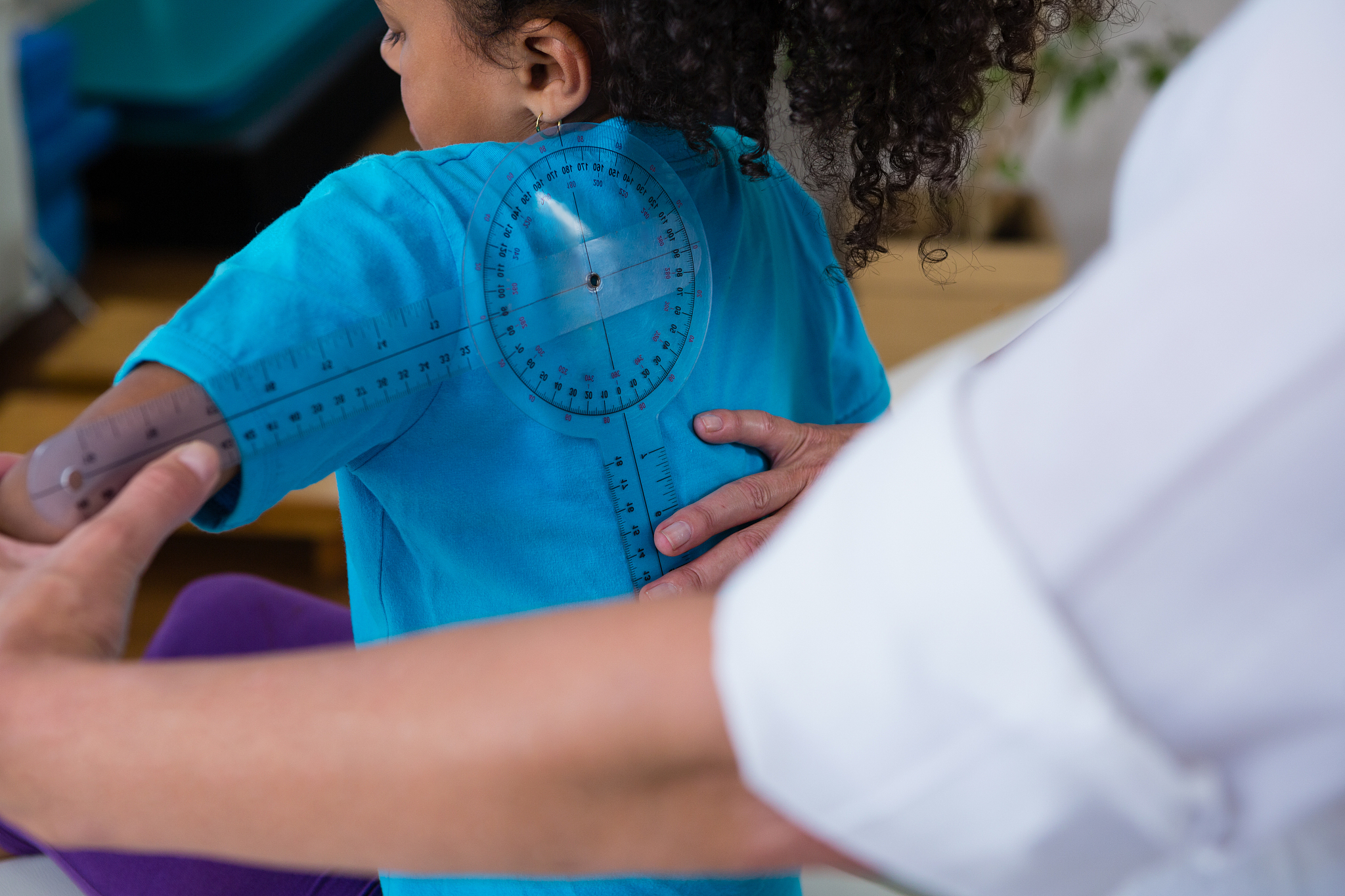 physiotherapist examining girl patients back with goniometer in 