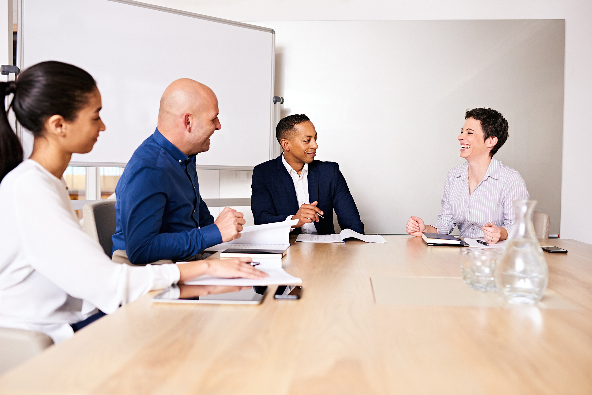 mature woman laughing at business meeting with three other peopl