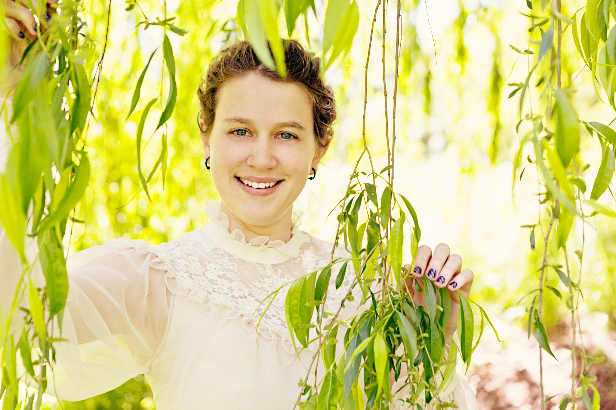 delicately beautiful young woman in romantic gown smiles under t