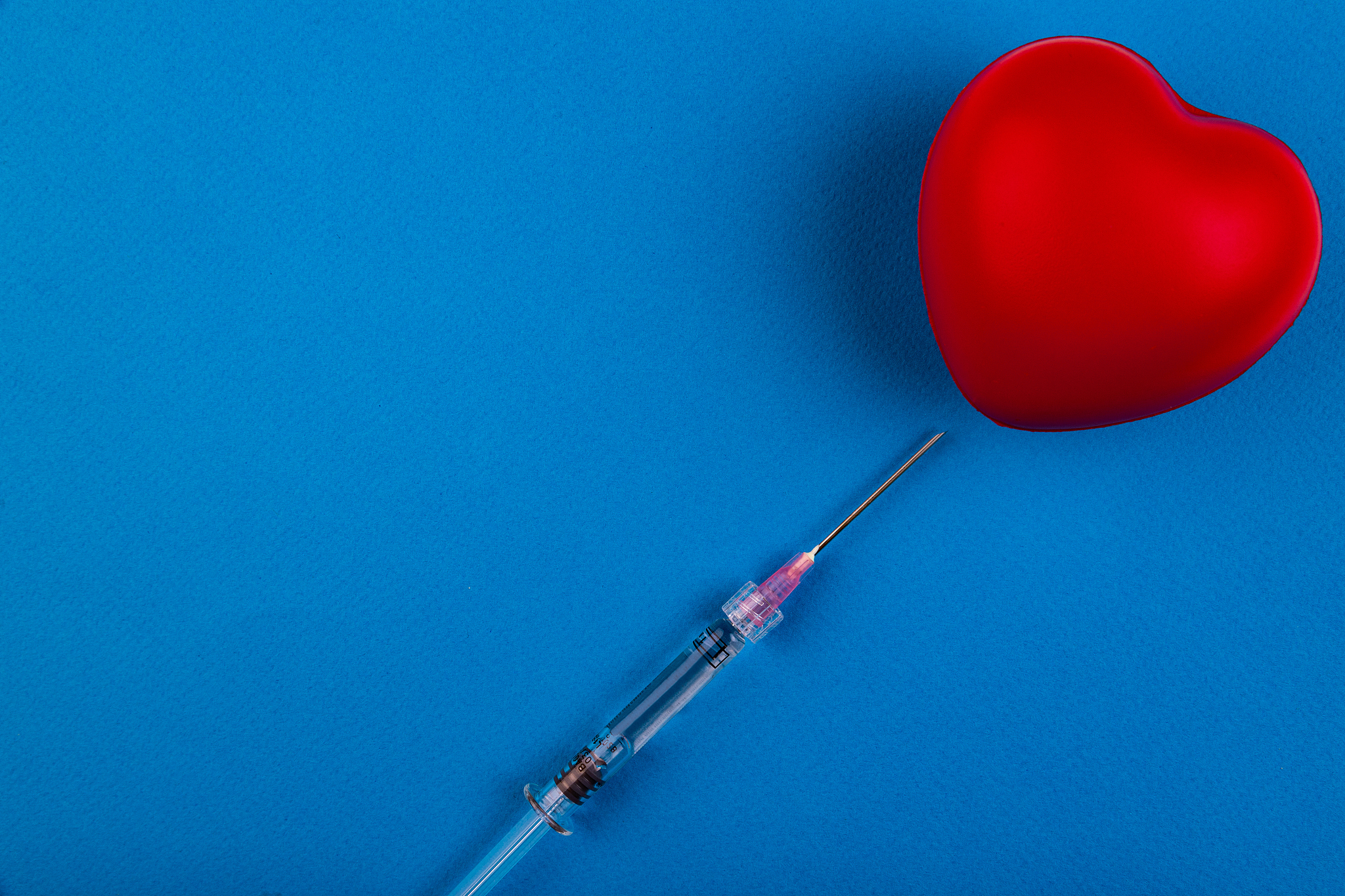 volumetric heart with a syringe on a blue background. the concep