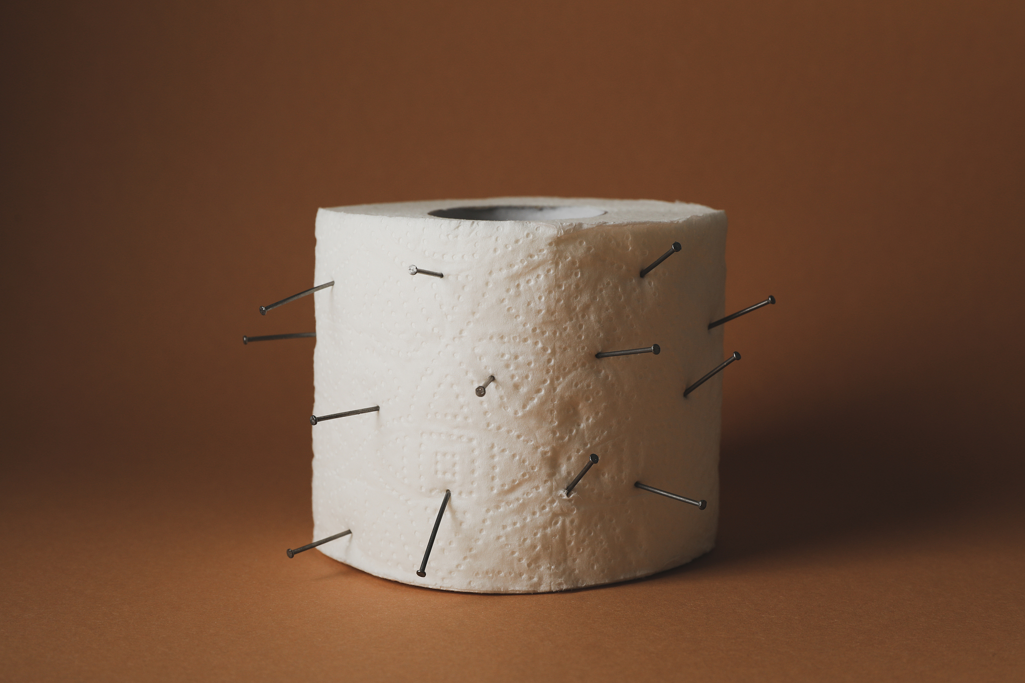 toilet paper with nails on brown craft background. hemorrhoids