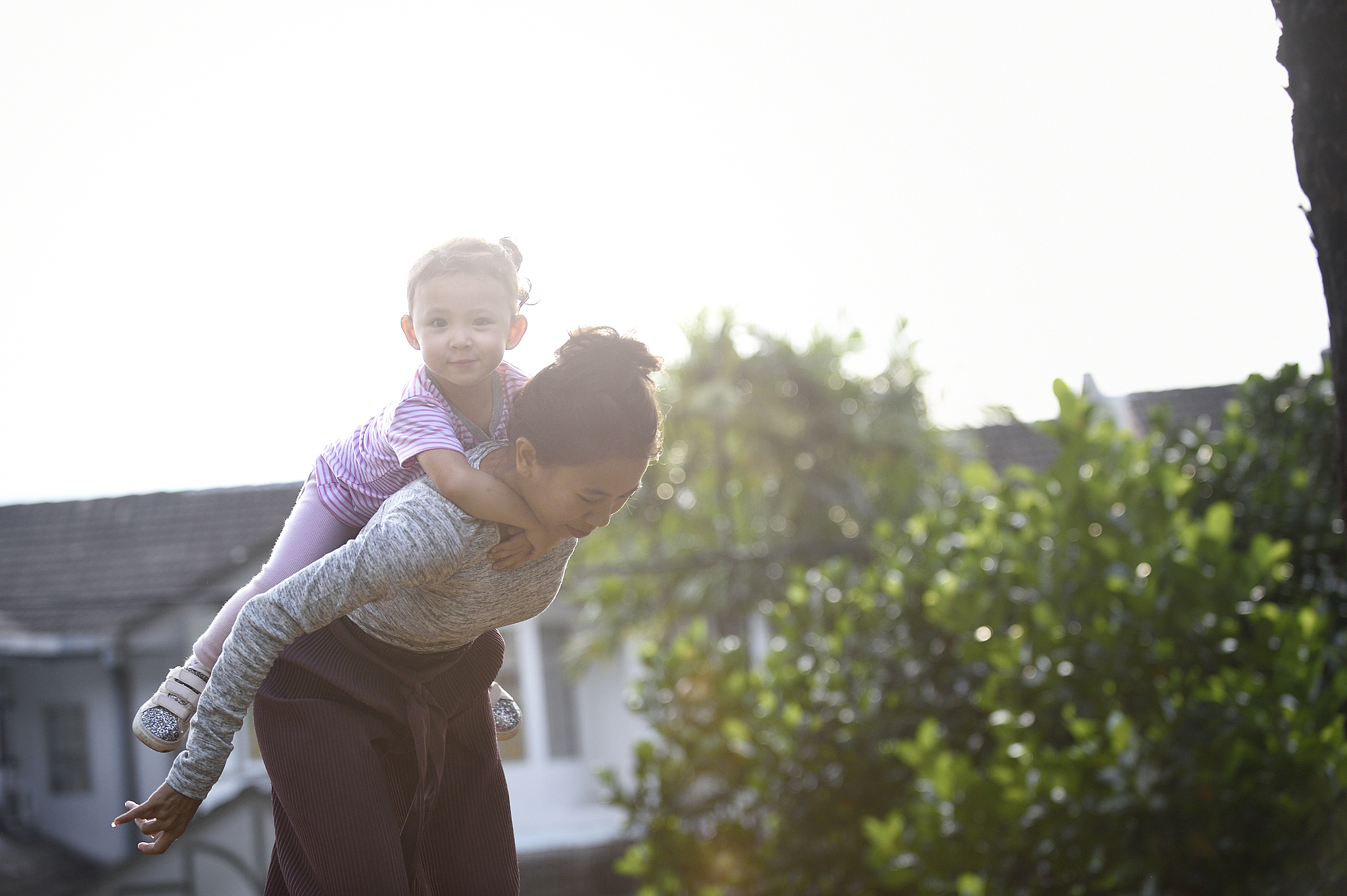 woman giving her daughter a piggy back ride in a park