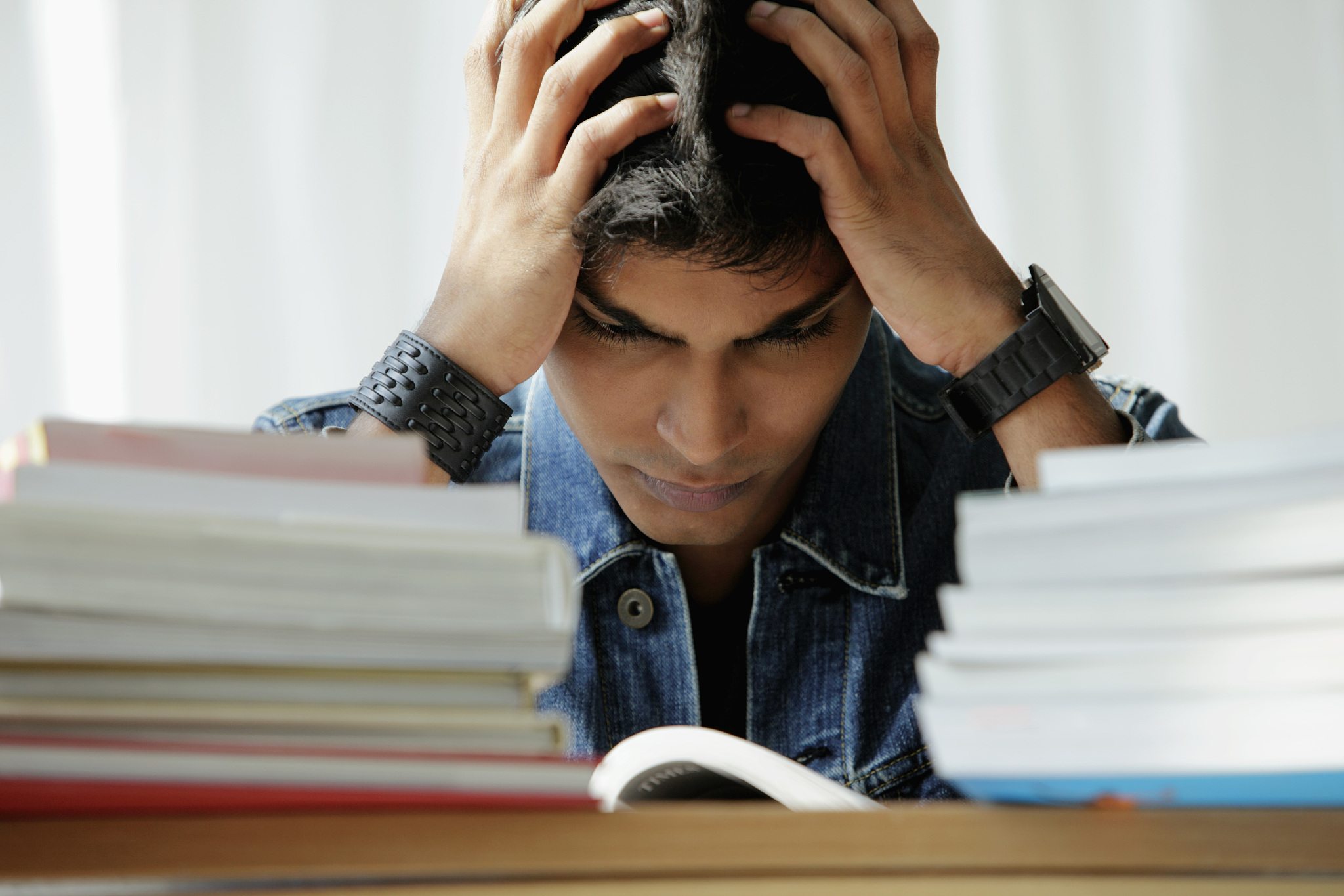 young man holding his head while reading