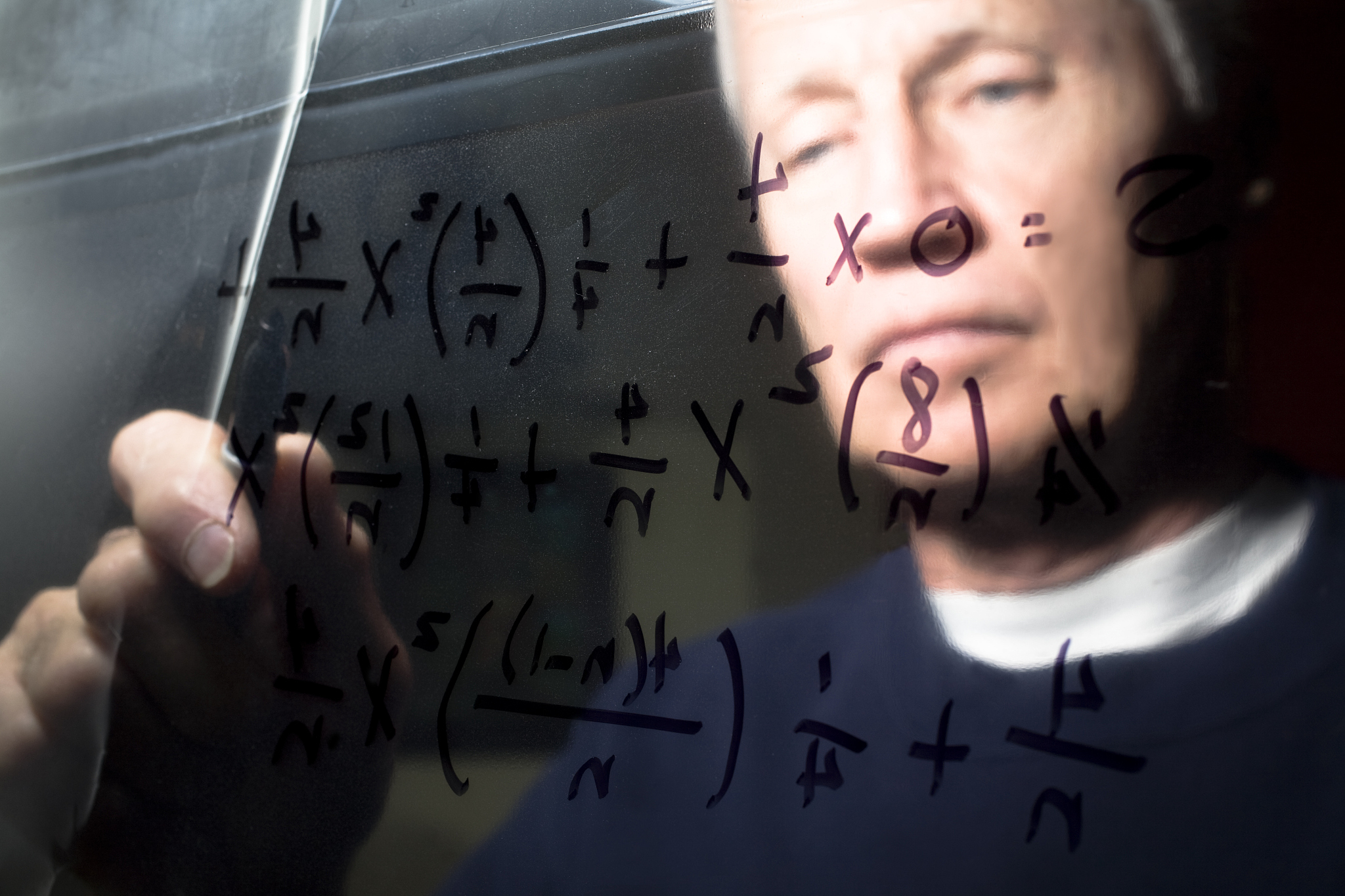 calculus equation on a clear dry erase board with man