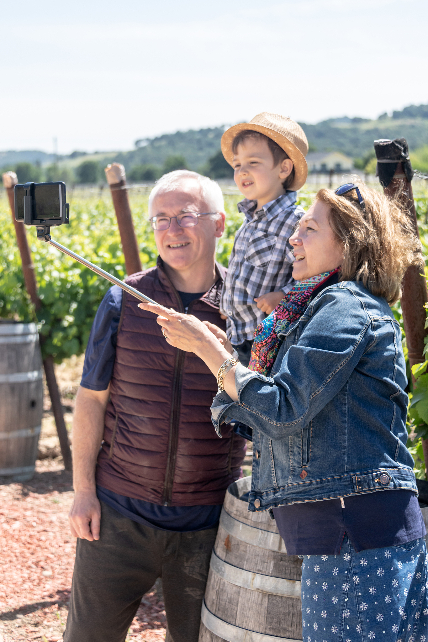 senior couple and their grandson taking a selfie at the vineyard