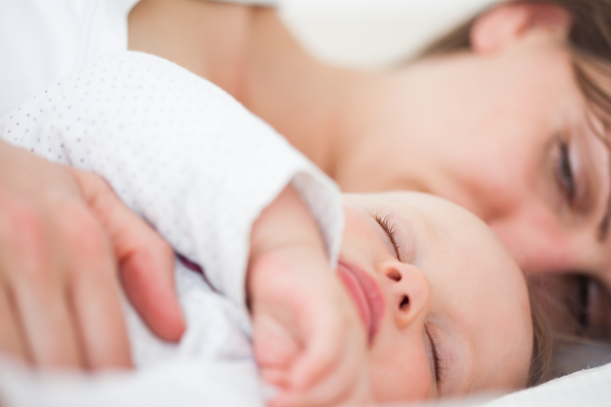 woman and her baby lying side by side in a room