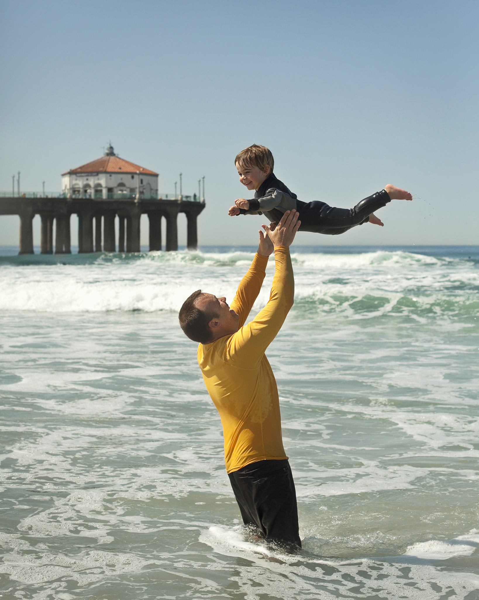 father tossing young son into air