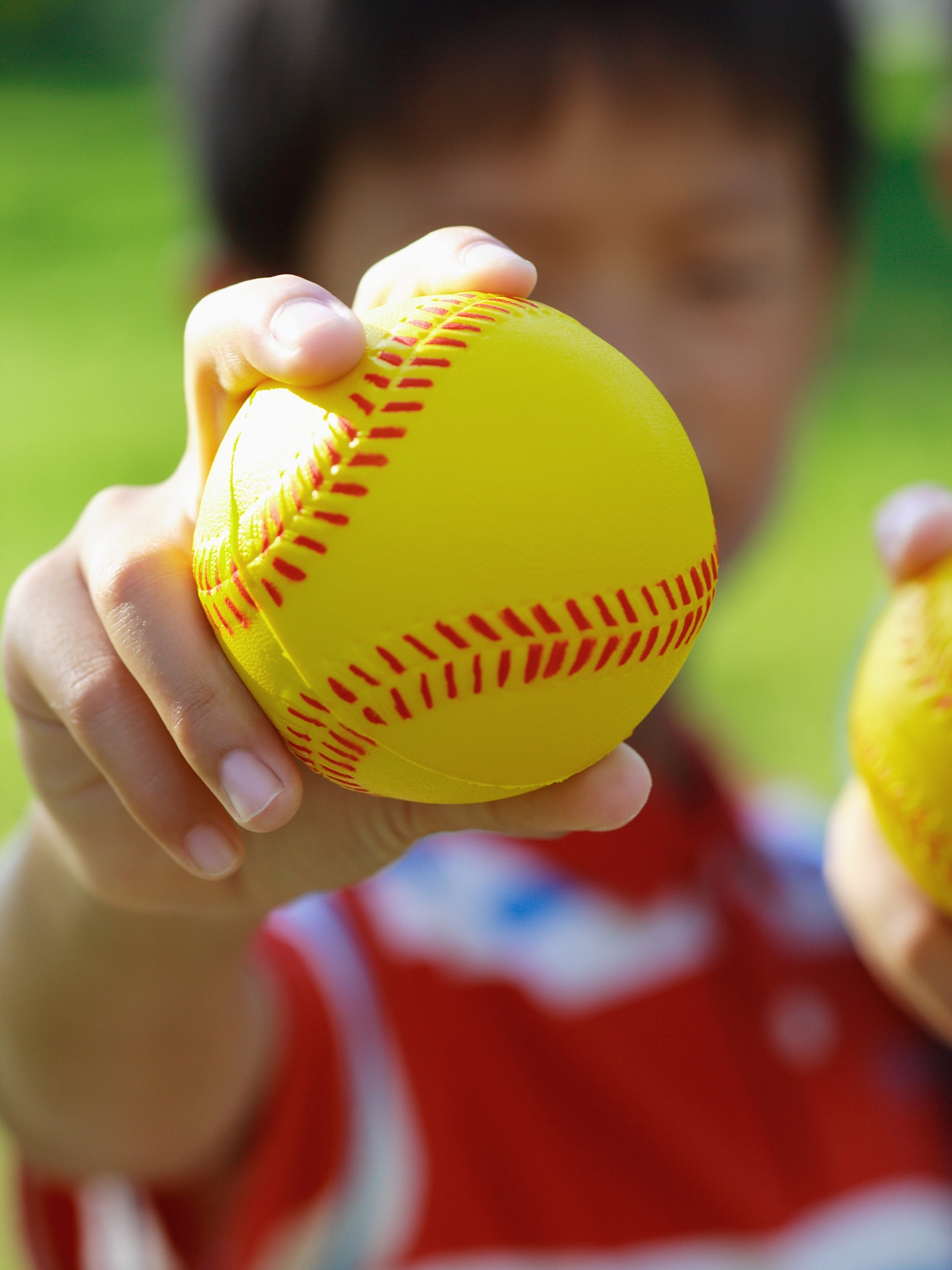 close-up of a boy showing a baseball