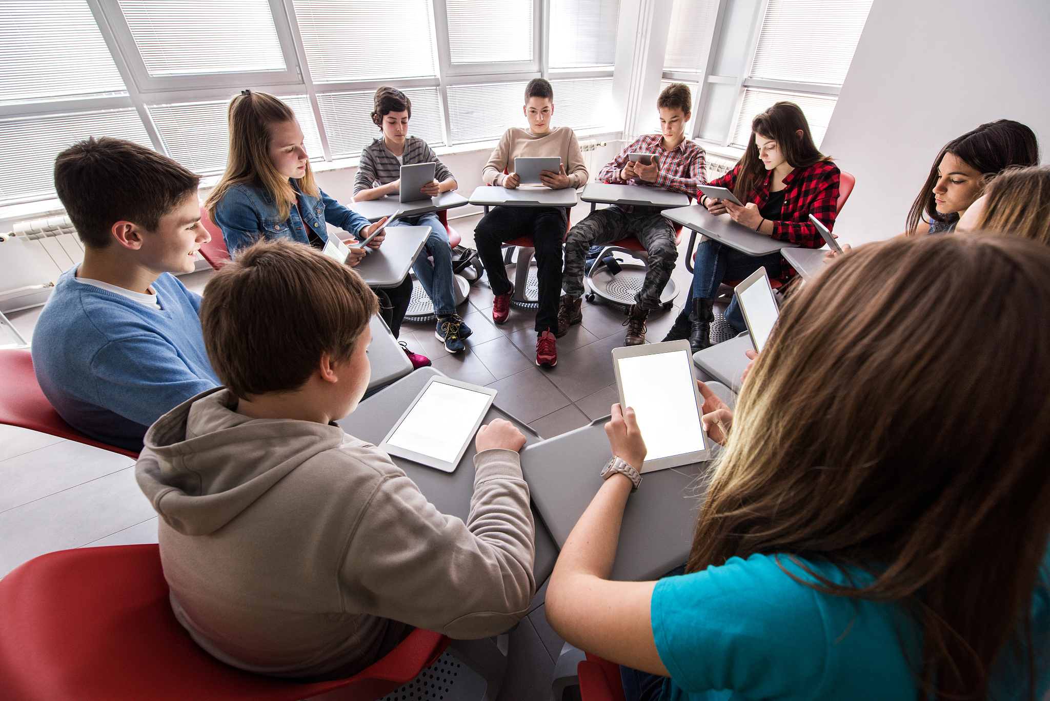 high school students using digital tablets in a circle.