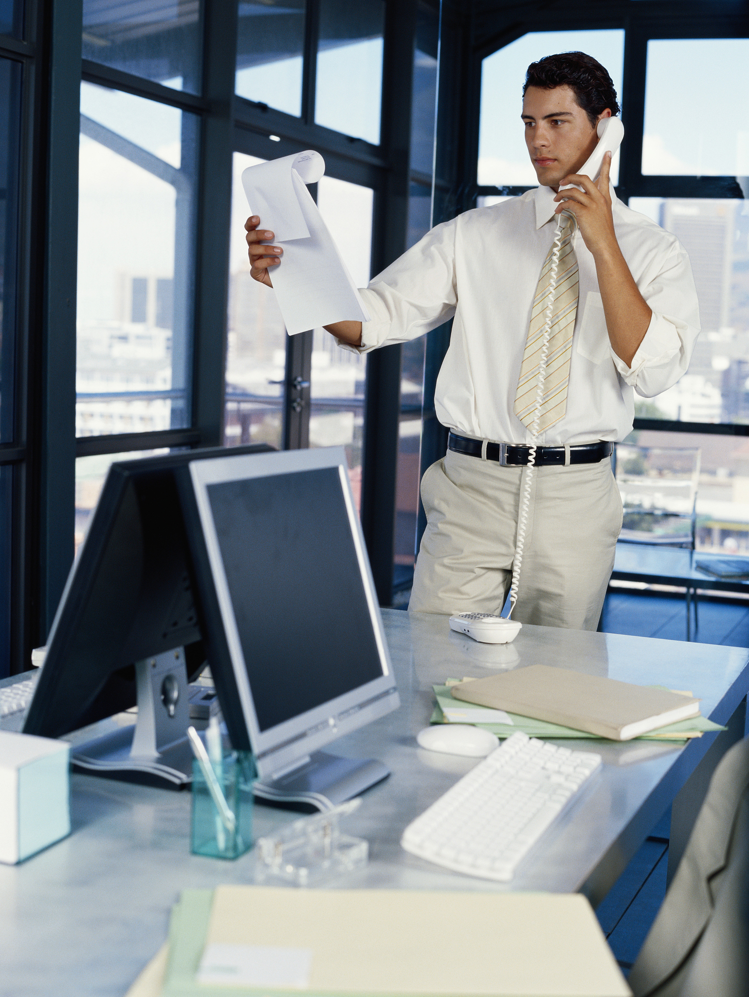 man holding document, using landline phone