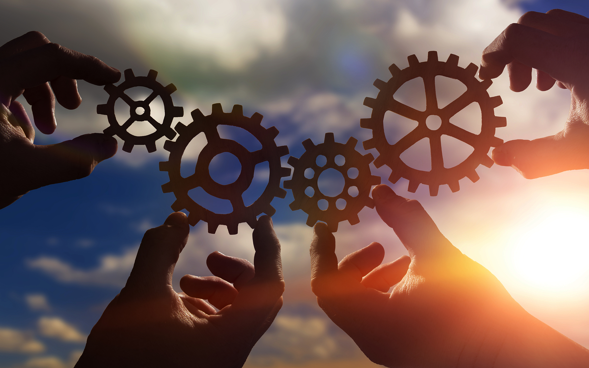 gears in the hands of people against the sky.