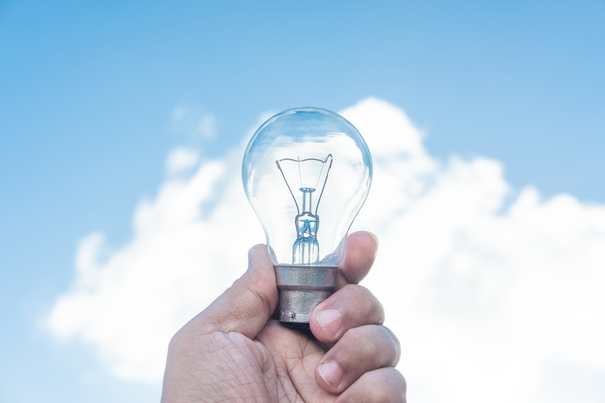 hand holding light bulb and blue sky background
