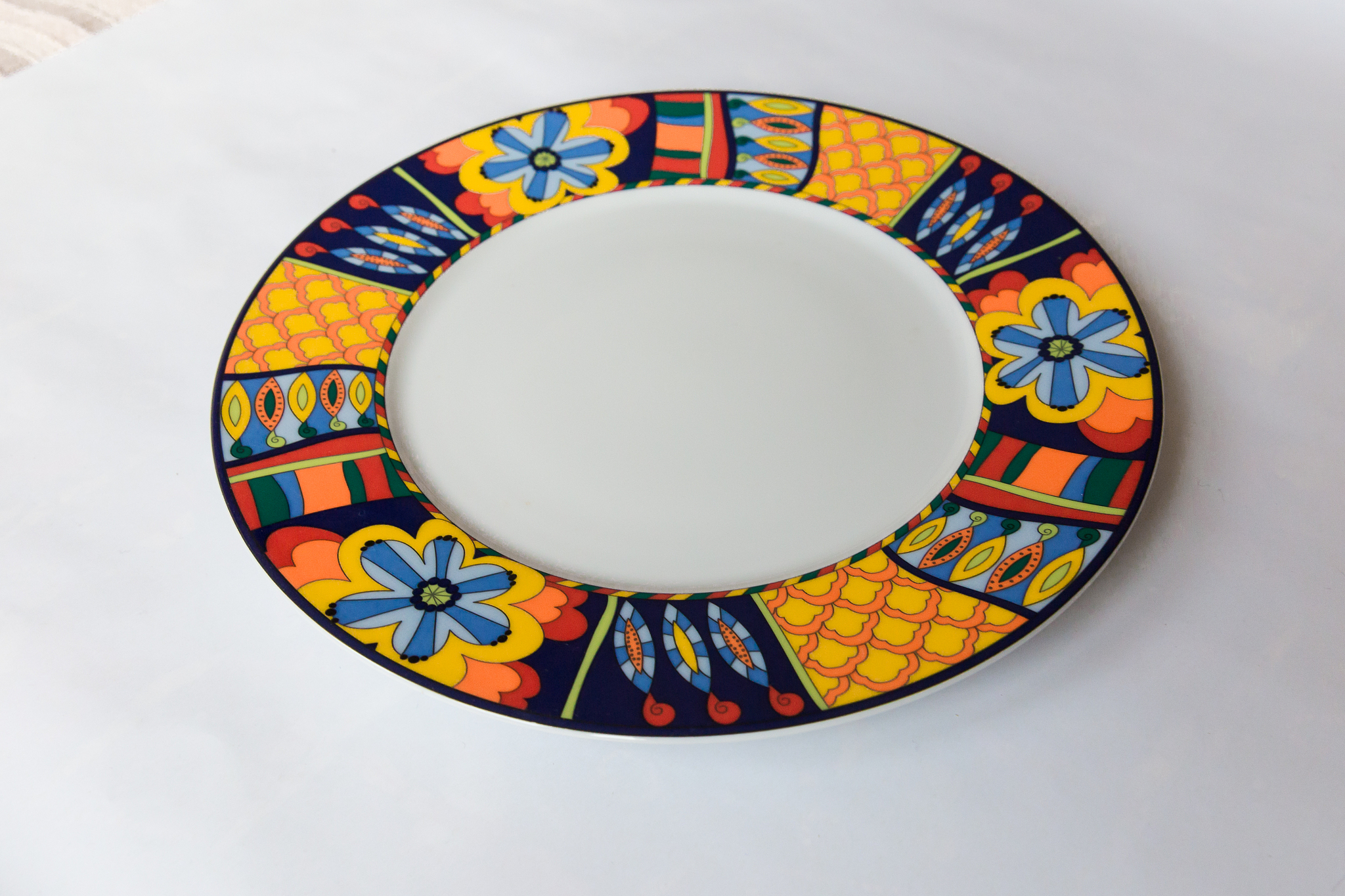a white round plate with floral and line pattern on white backgr