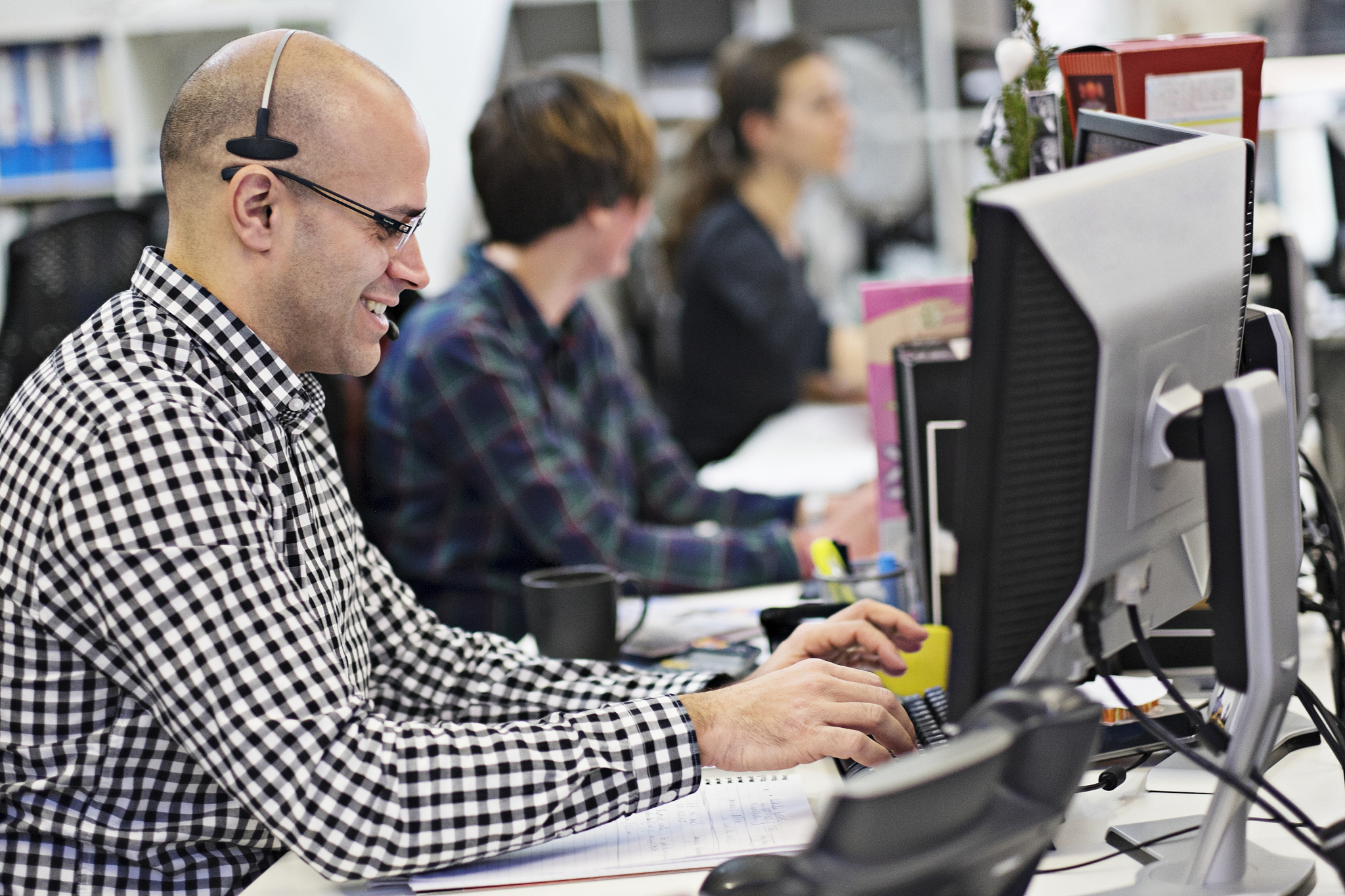 people working in office, desks with computer monitors, selectiv