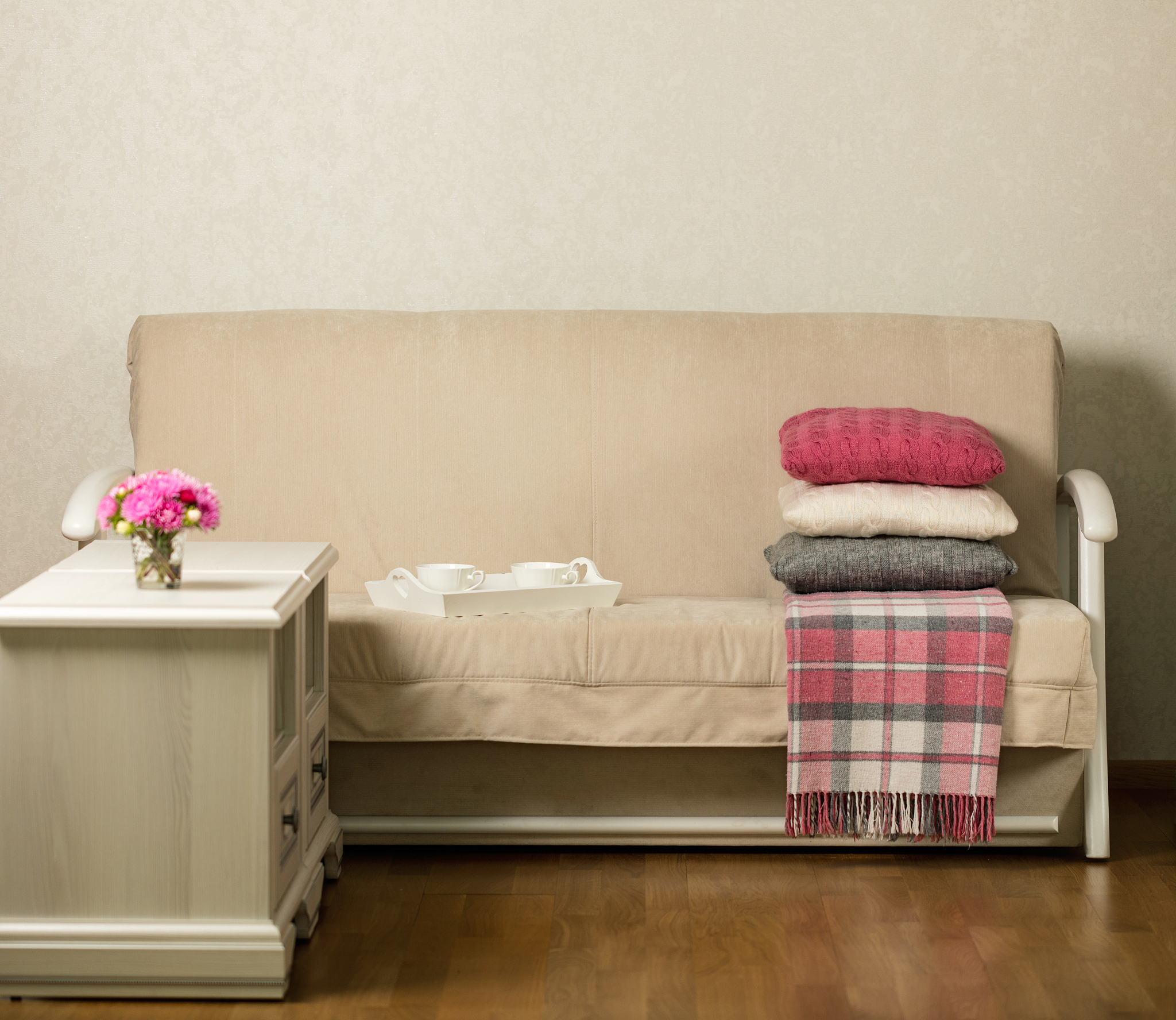 beige sofa with pillows in the living room and vase with flowers