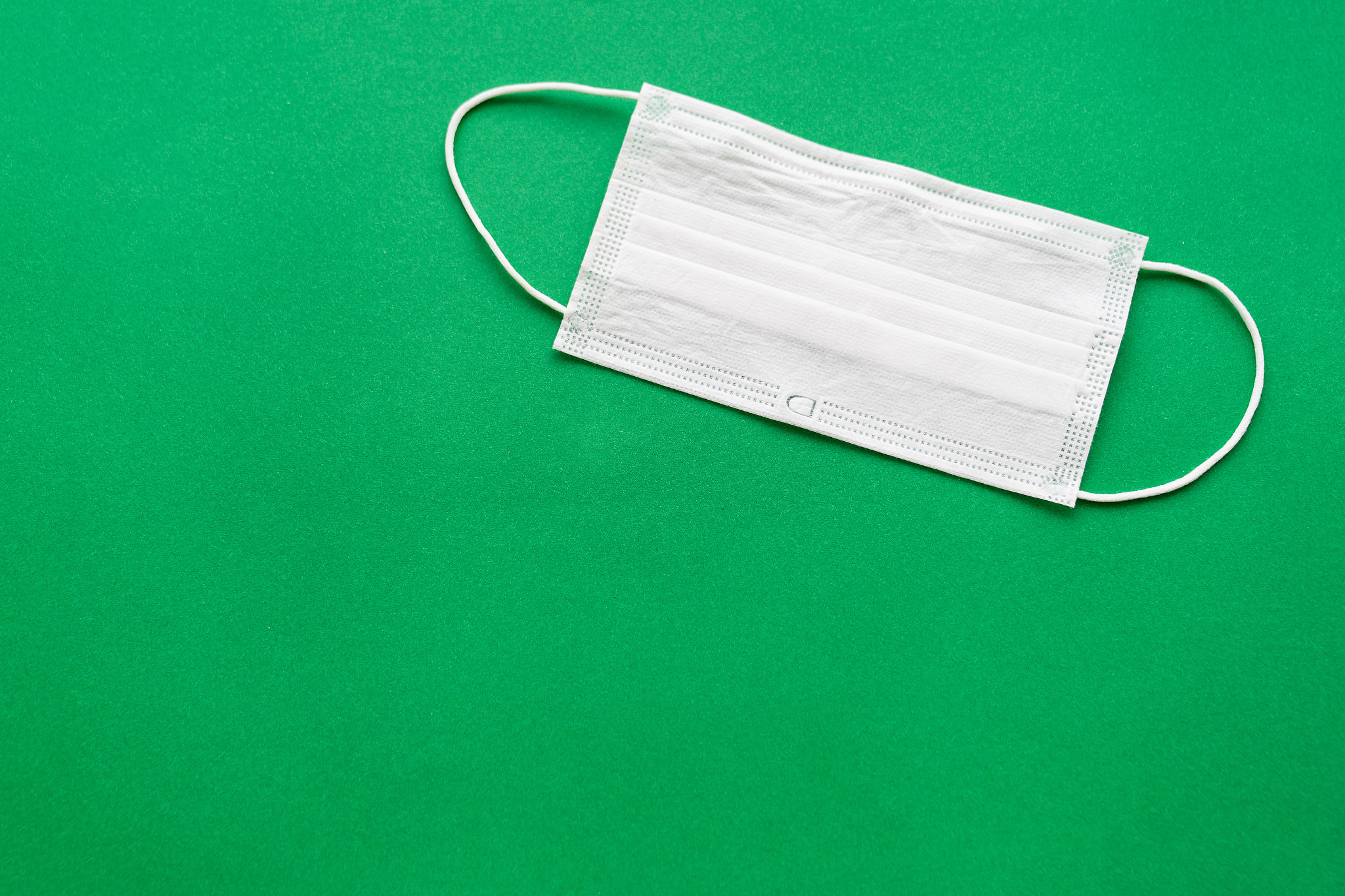 a disposable medical mask on a green background.