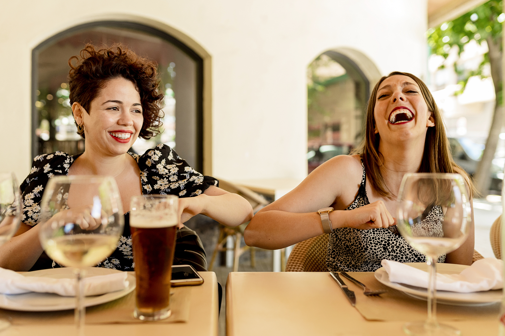 cheerful young women greeting with elbow bump while sitting and 